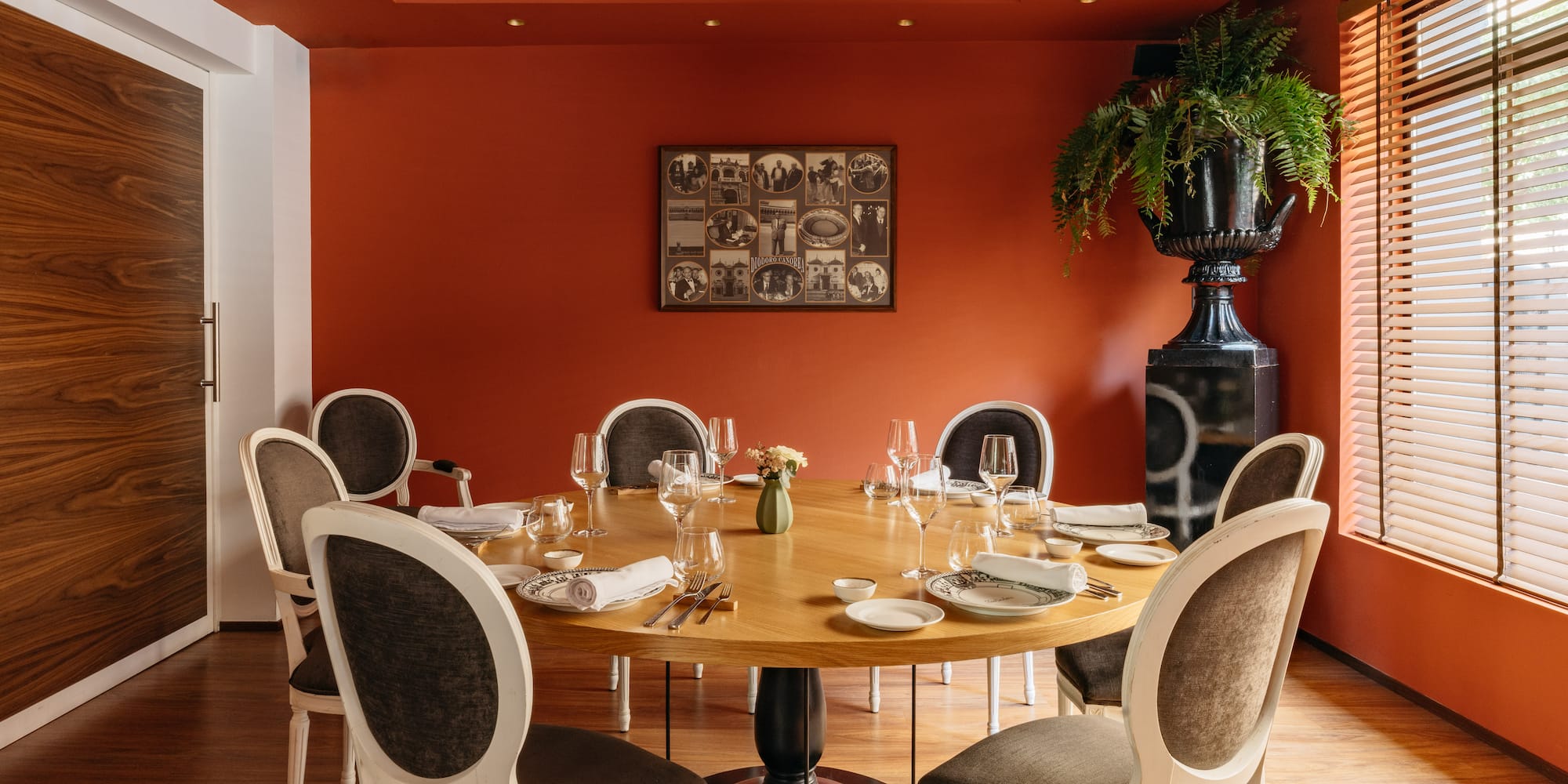 Comedor de restaurante elegante con mesa redonda, sillas y paredes terracota.