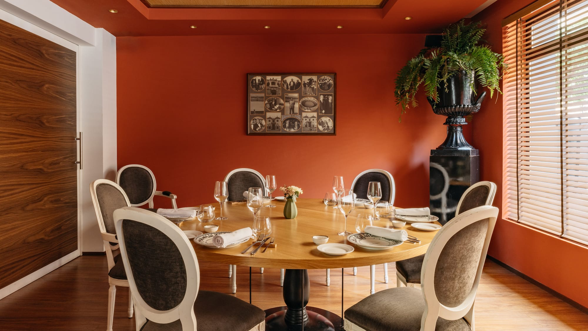 Comedor de restaurante elegante con mesa redonda, sillas y paredes terracota.