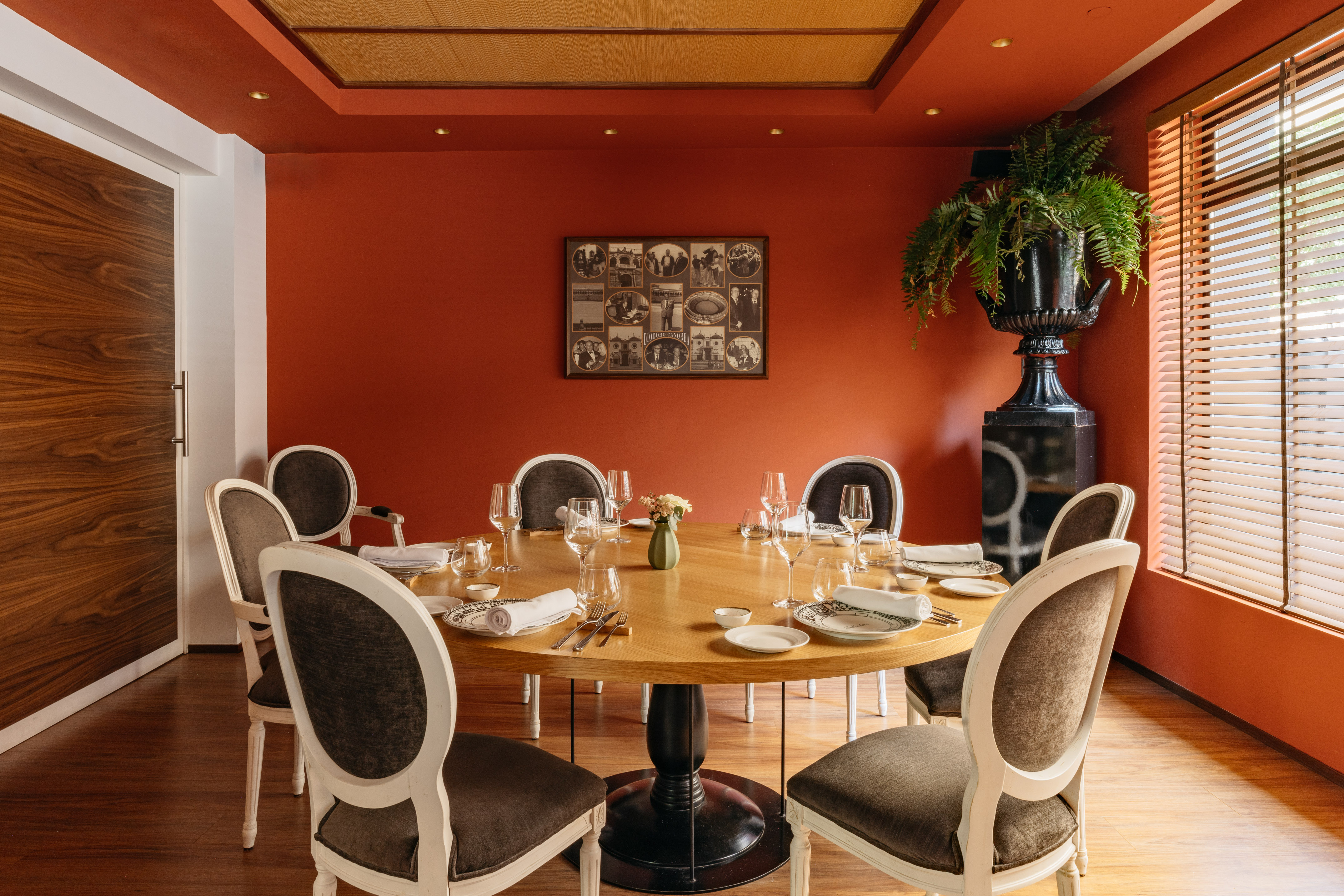 Comedor de restaurante elegante con mesa redonda, sillas y paredes terracota.