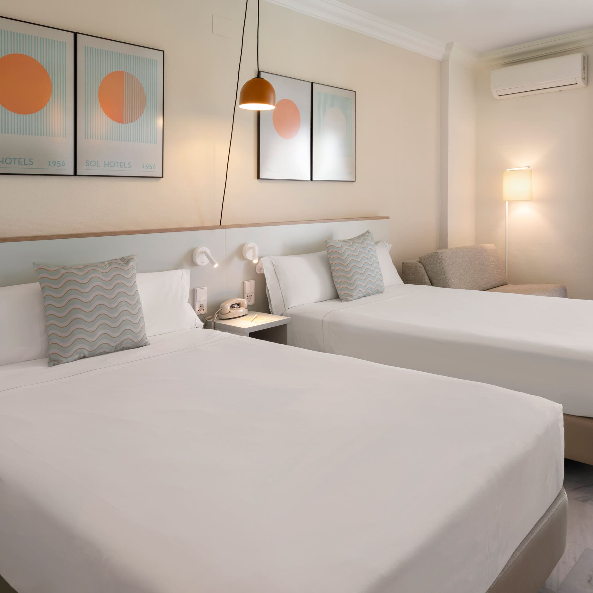 Bright hotel room with twin beds, balcony, city view, and modern furnishings.