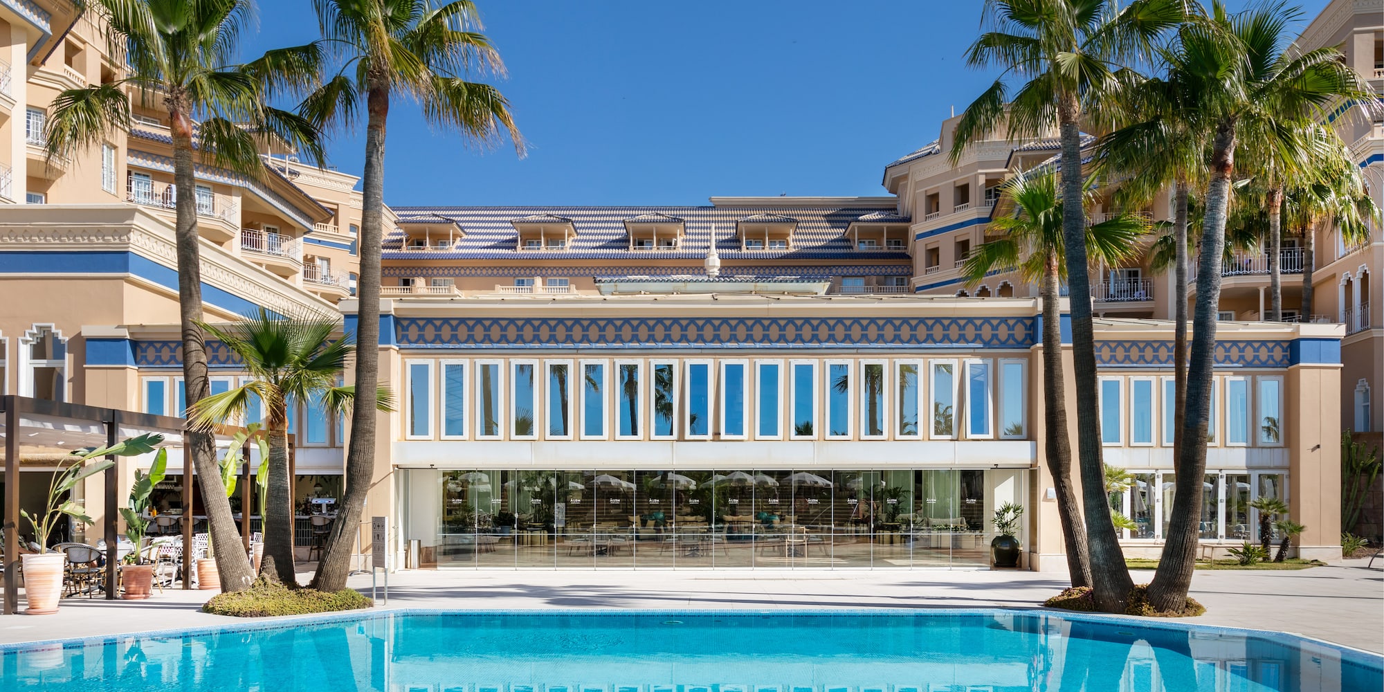 a pool with palm trees in front of a building