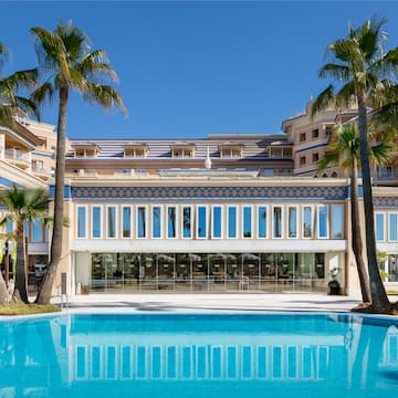 a pool with palm trees in front of a building
