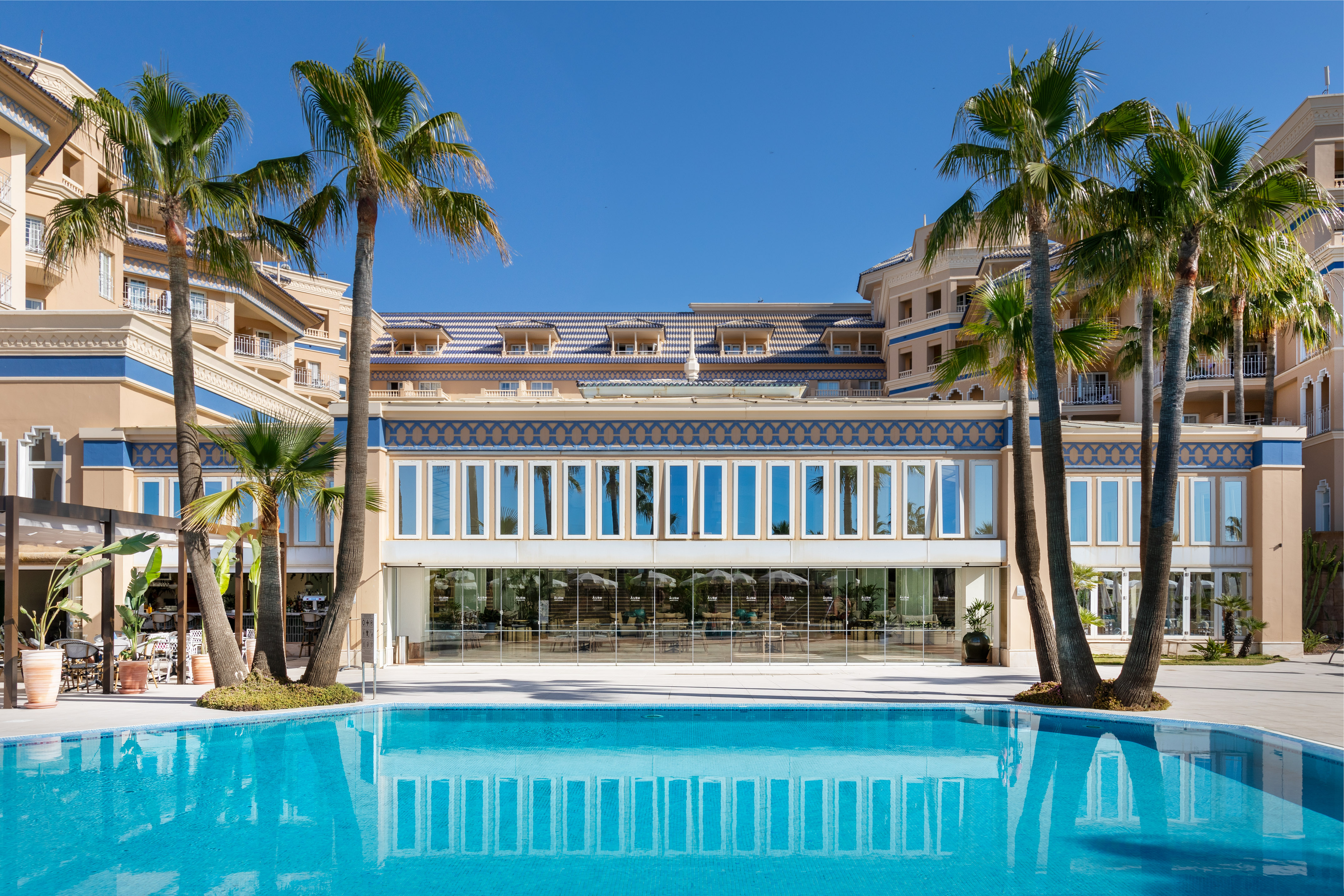 a pool with palm trees in front of a building