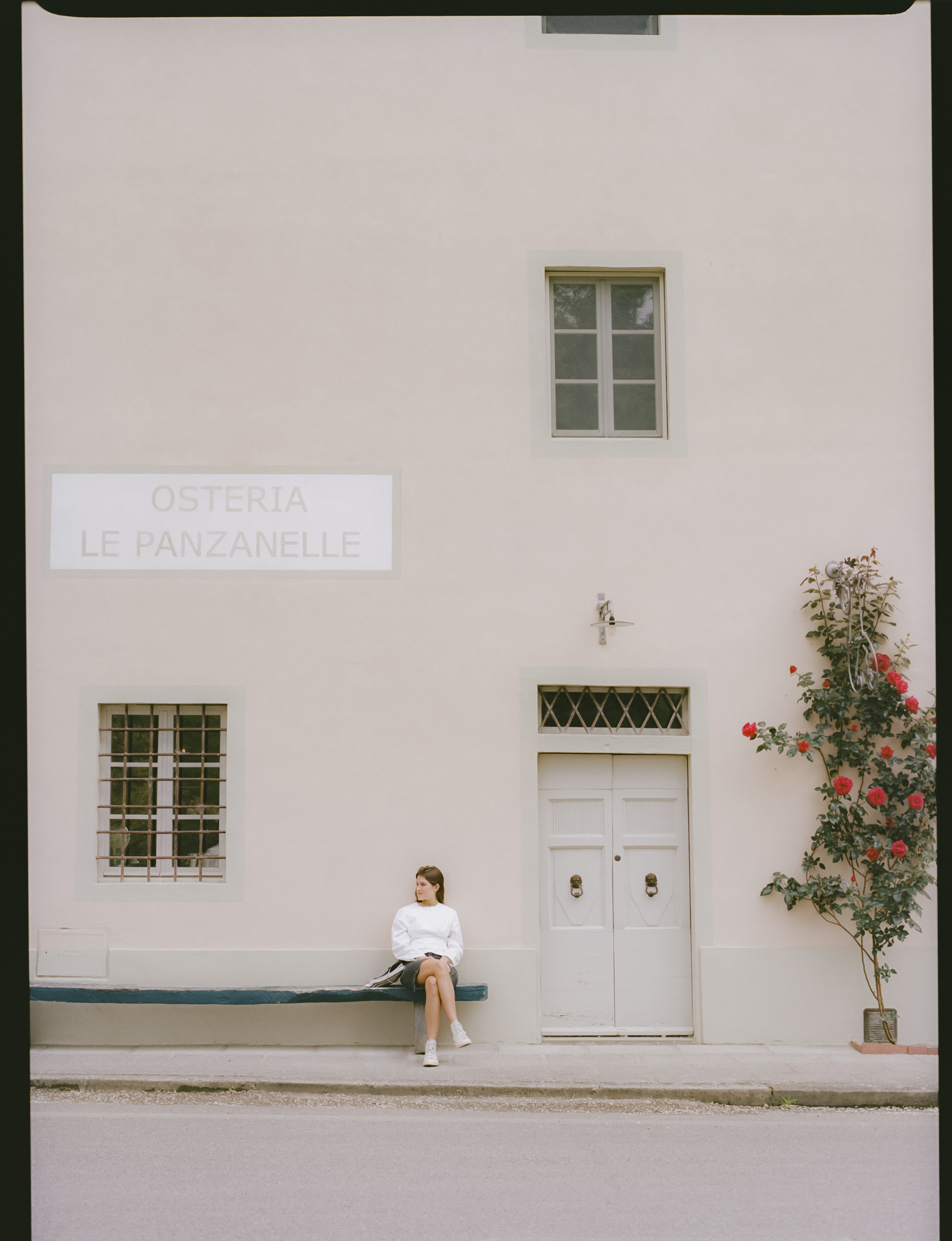 a woman sitting on a bench outside of a building
