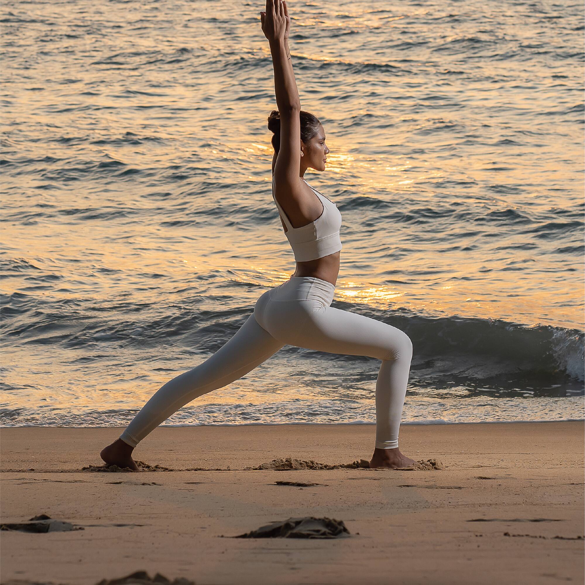 a woman in yoga pose on a beach