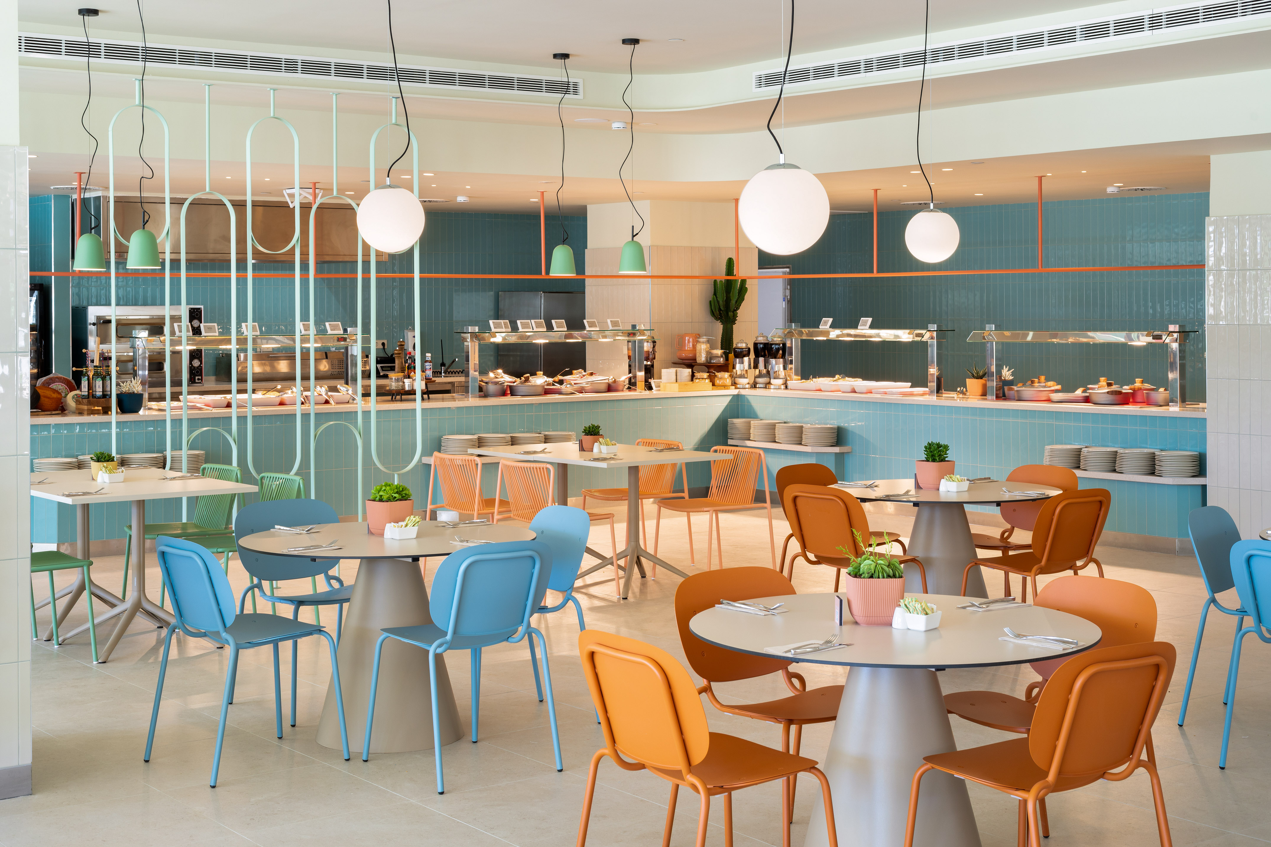 Vibrant modern buffet restaurant with colorful chairs, teal decor and food stations.