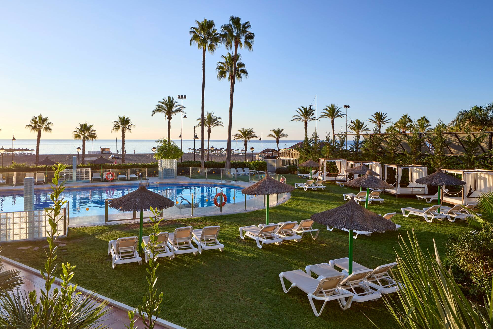 a pool with lounge chairs and umbrellas and palm trees