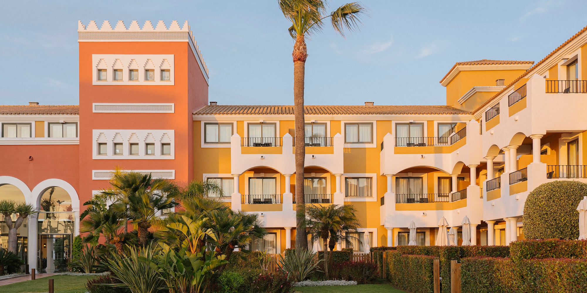Vibrant Mediterranean resort hotel with lush gardens and palm trees.
