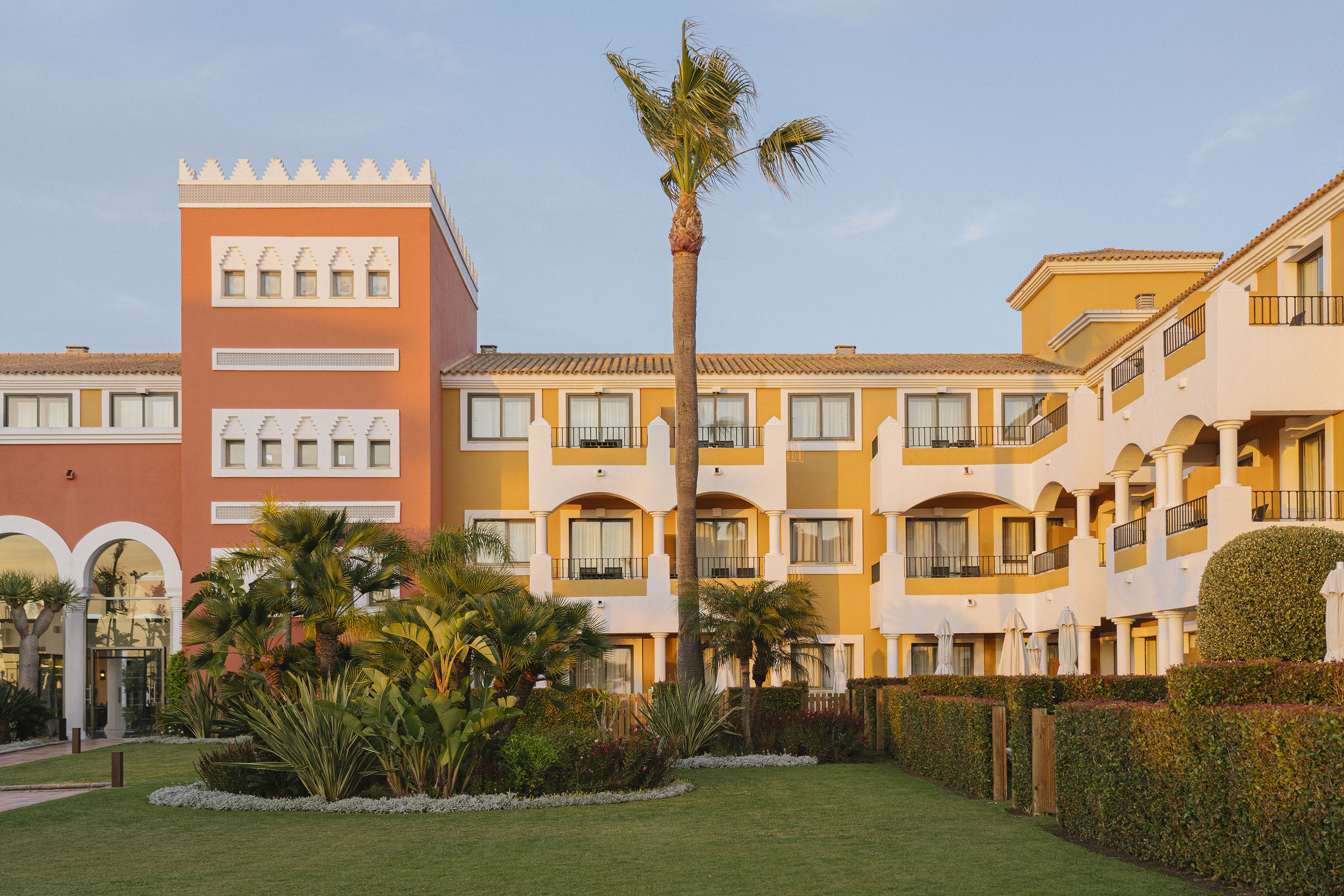 Vibrant Mediterranean resort hotel with lush gardens and palm trees.