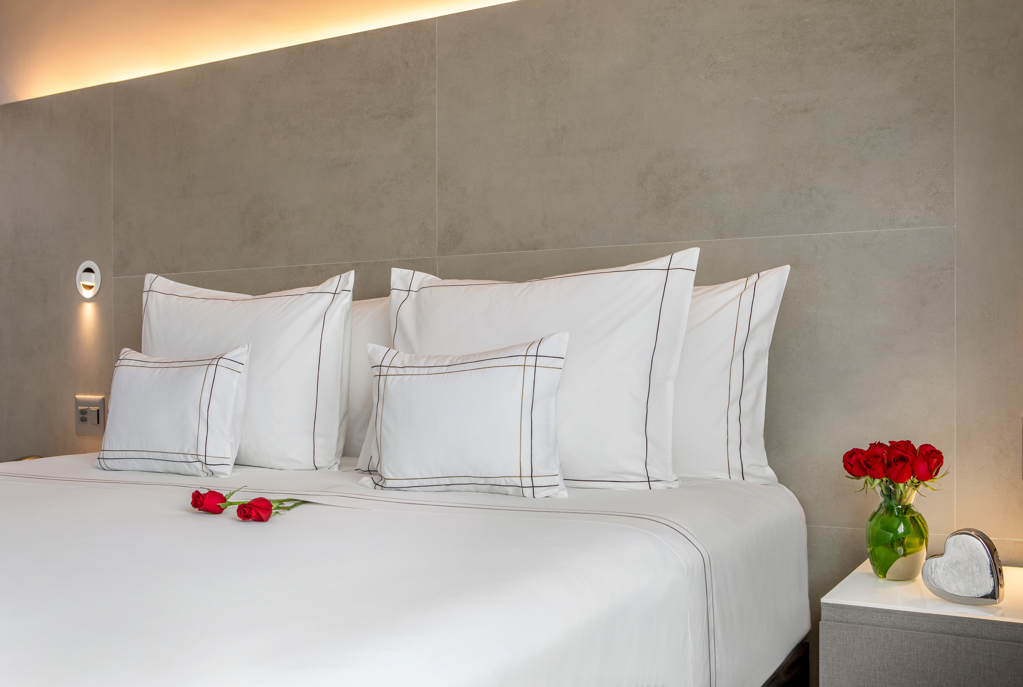 a bed with white pillows and red roses