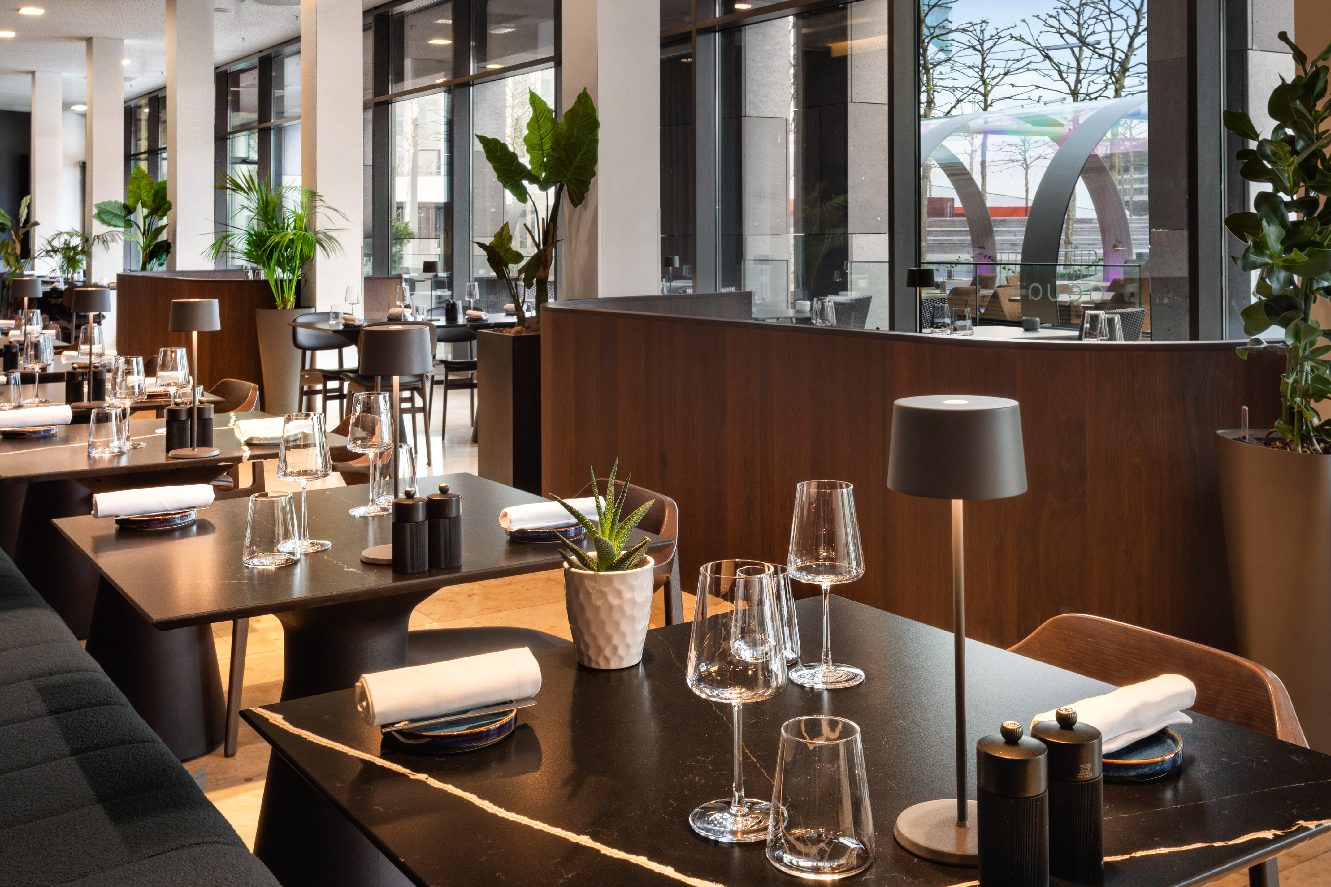 Upscale modern restaurant dining room with set tables and large windows.