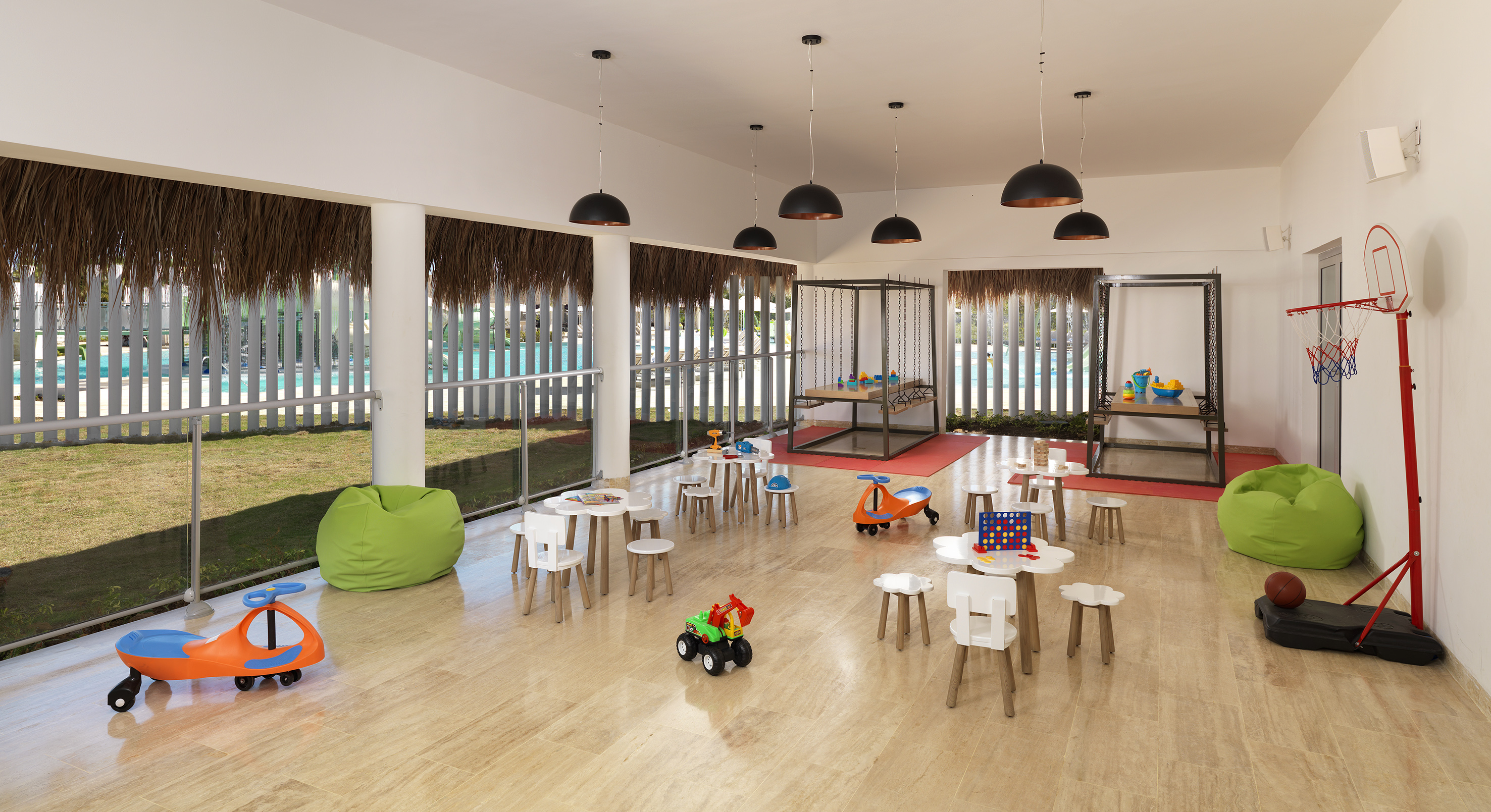 Kids club play area with toys, tables, bean bags, and pool view.