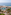 Aerial view of luxury beachfront resort with large swimming pool, palm trees, and ocean.