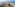 Aerial view of luxury beachfront resort with large swimming pool, palm trees, and ocean.