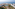 Aerial view of luxury beachfront resort with large swimming pool, palm trees, and ocean.