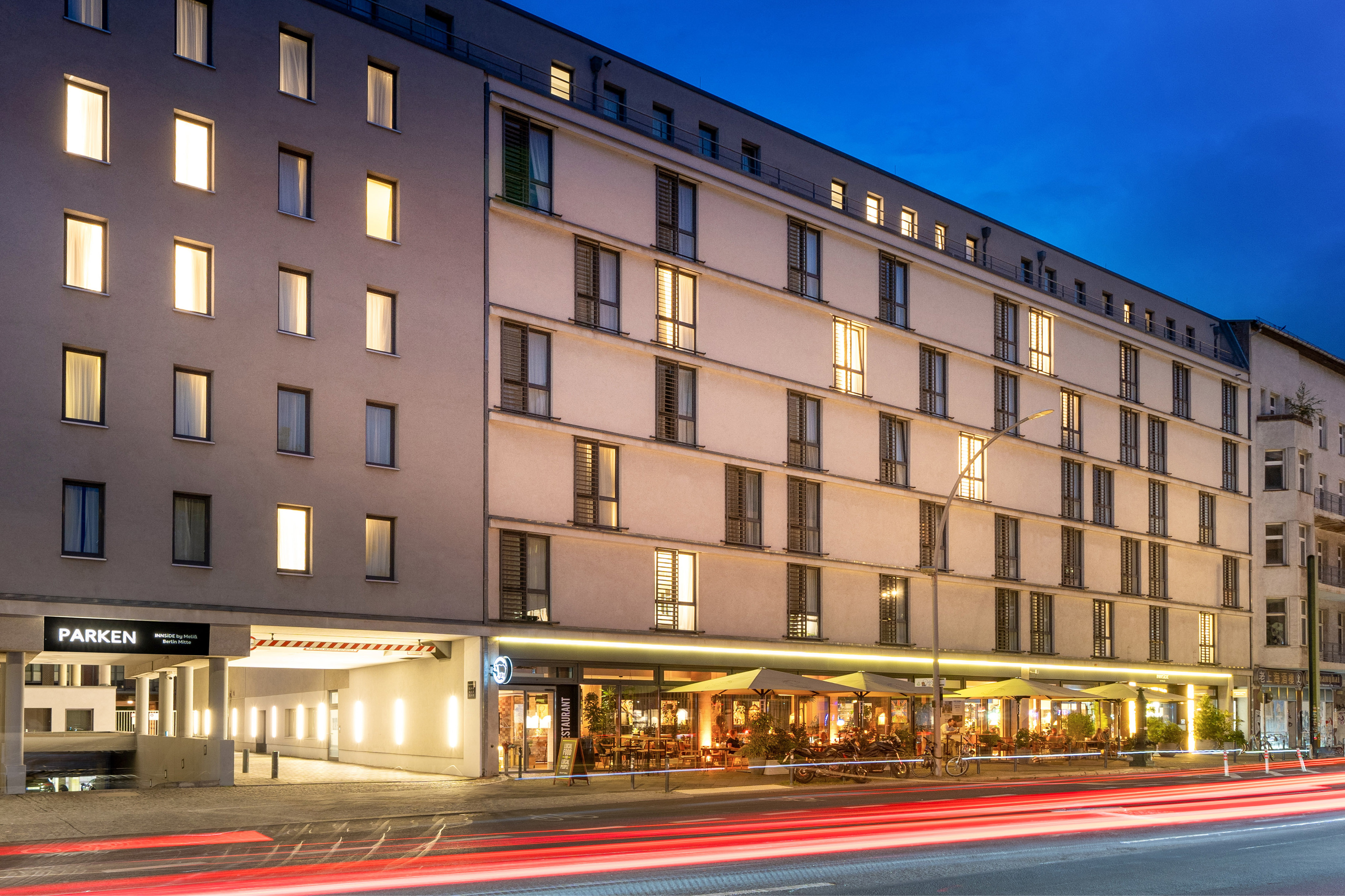 INNSIDE Berlin Mitte hotel, evening restaurant patio, and parking entrance.