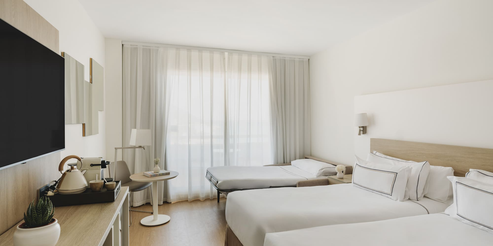 Habitación hotel moderna, dos camas individuales, sofá cama, TV.