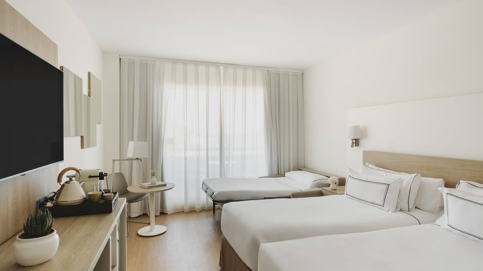 Habitación hotel moderna, dos camas individuales, sofá cama, TV.