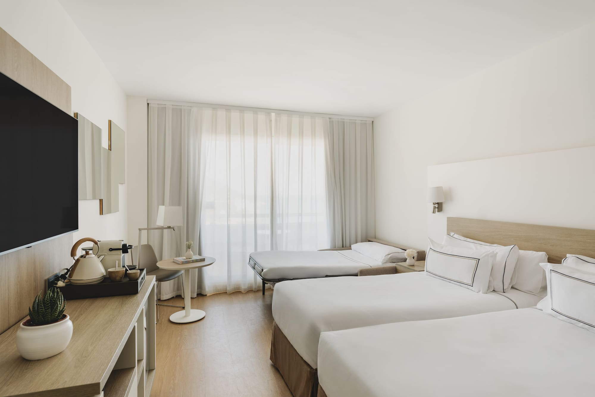 Habitación hotel moderna, dos camas individuales, sofá cama, TV.