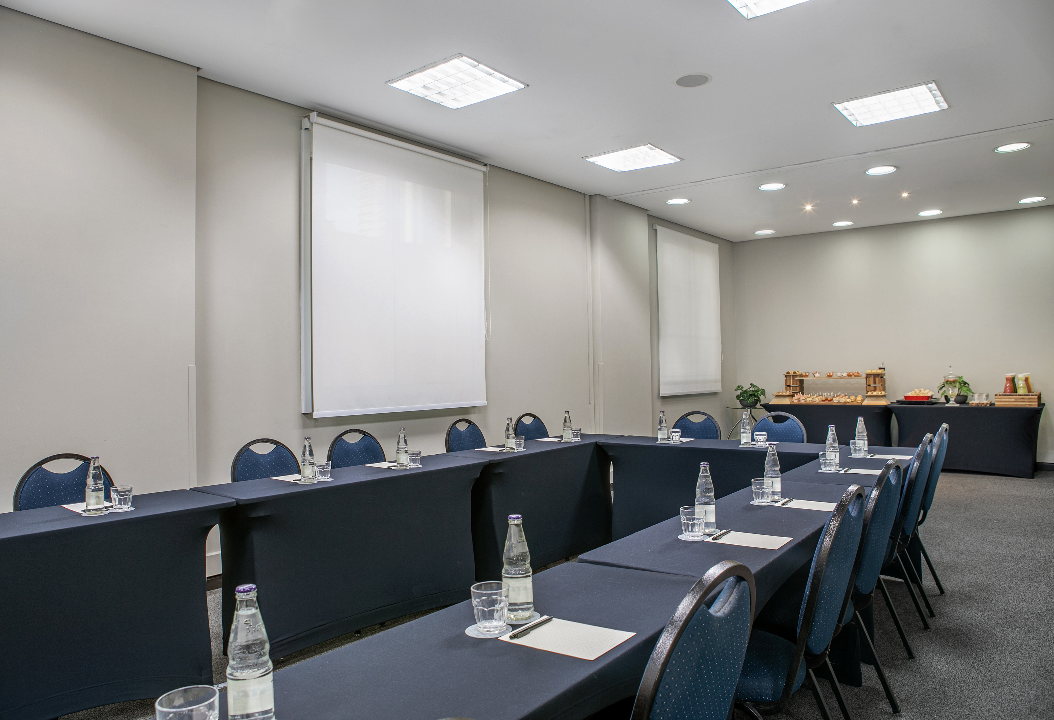 U-shaped conference room with blue chairs, water, and refreshments.