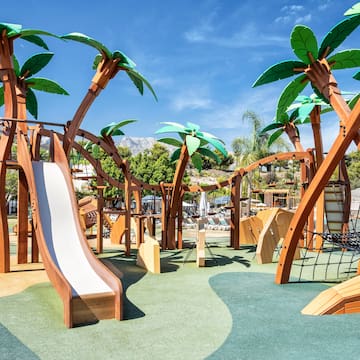 a playground with palm trees and a slide