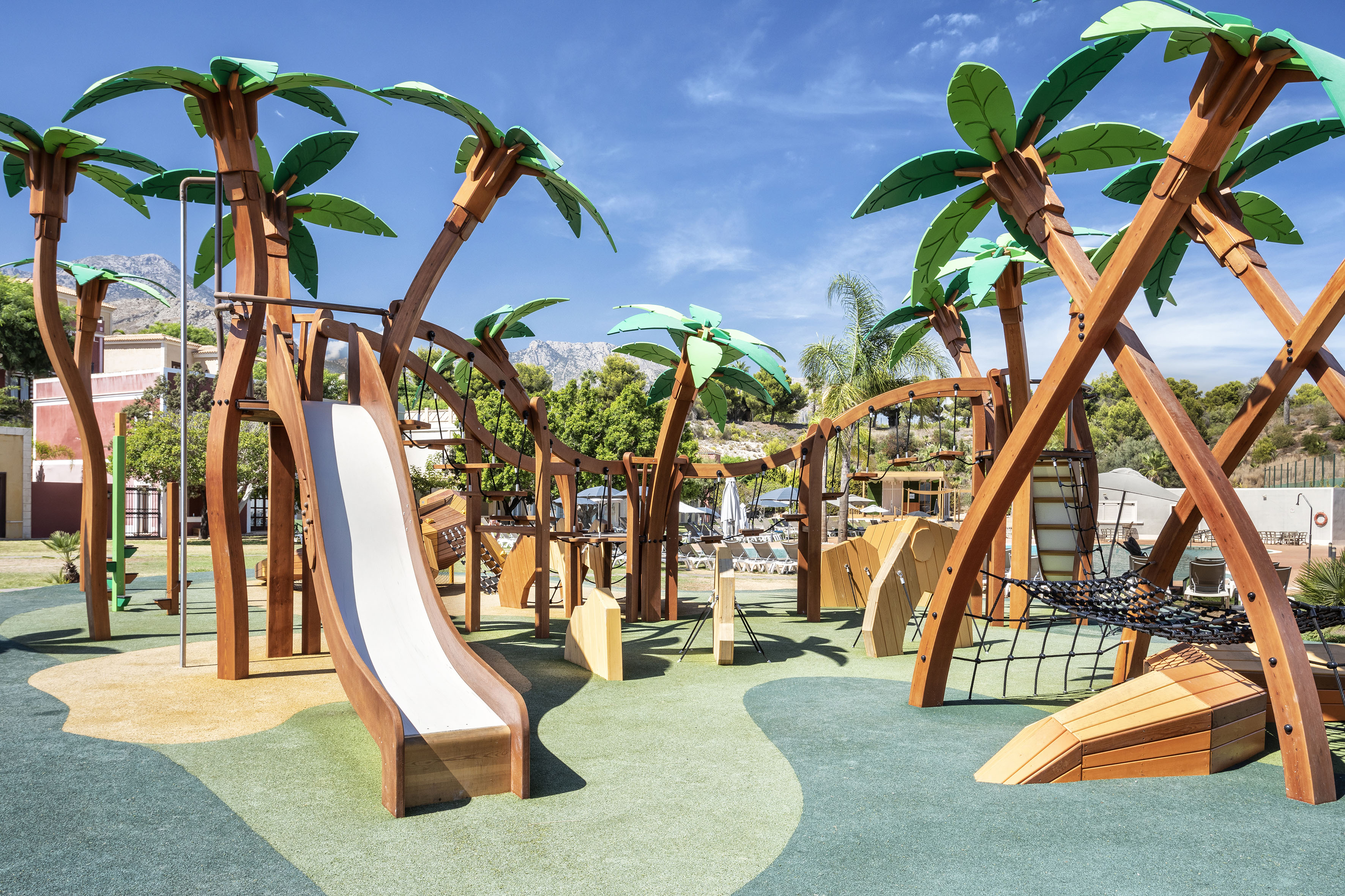 Colorful palm tree themed outdoor playground with slide and climbing features.