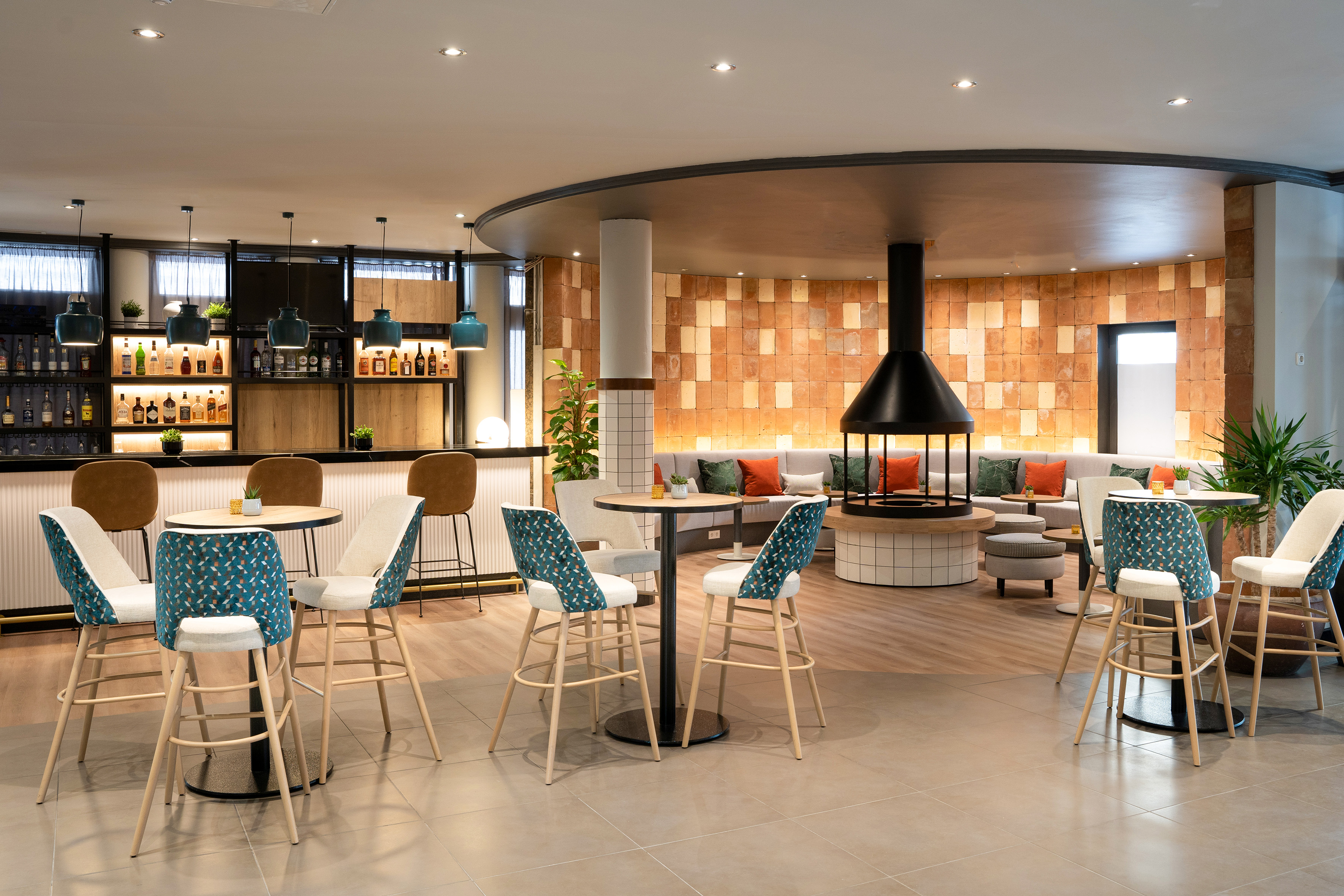 Modern hotel bar and lounge with circular fireplace, stylish seating, and liquor display.