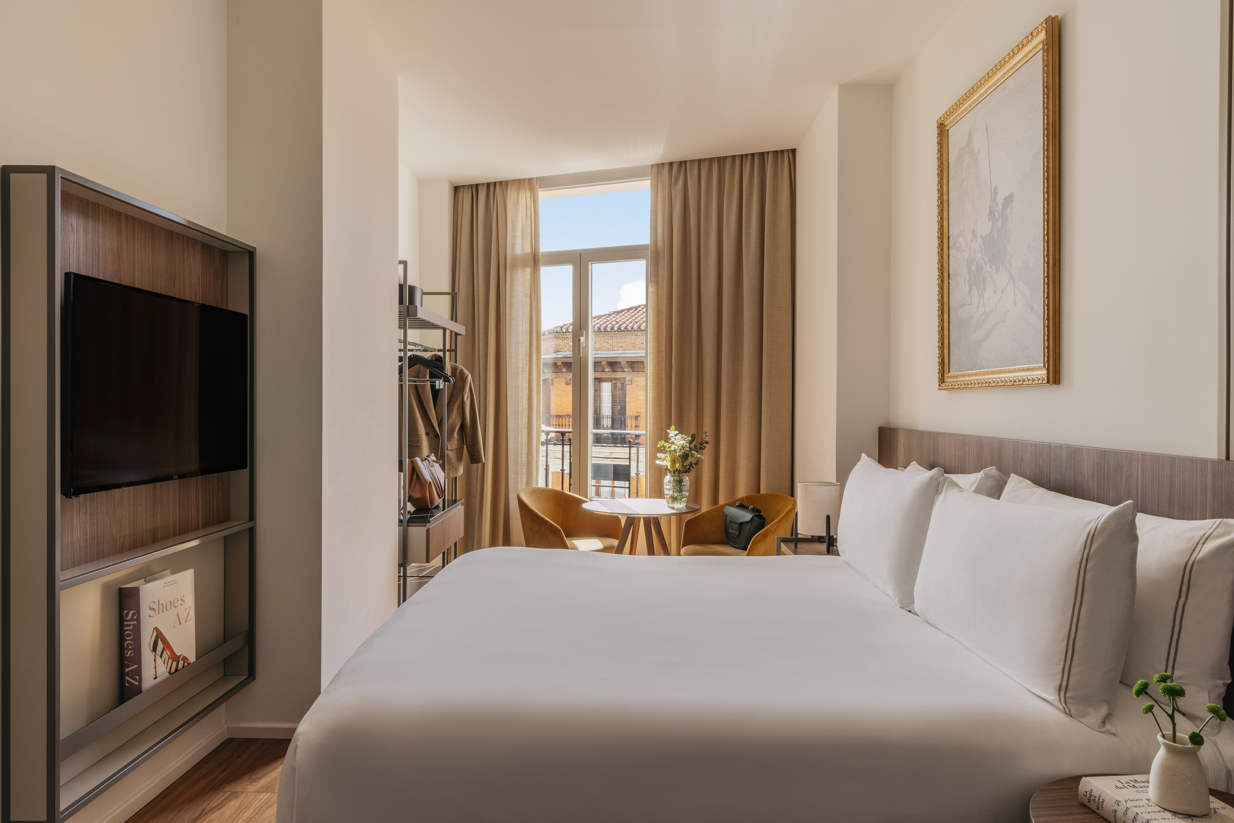 Stylish hotel room with king bed, window seating, TV, and modern decor.