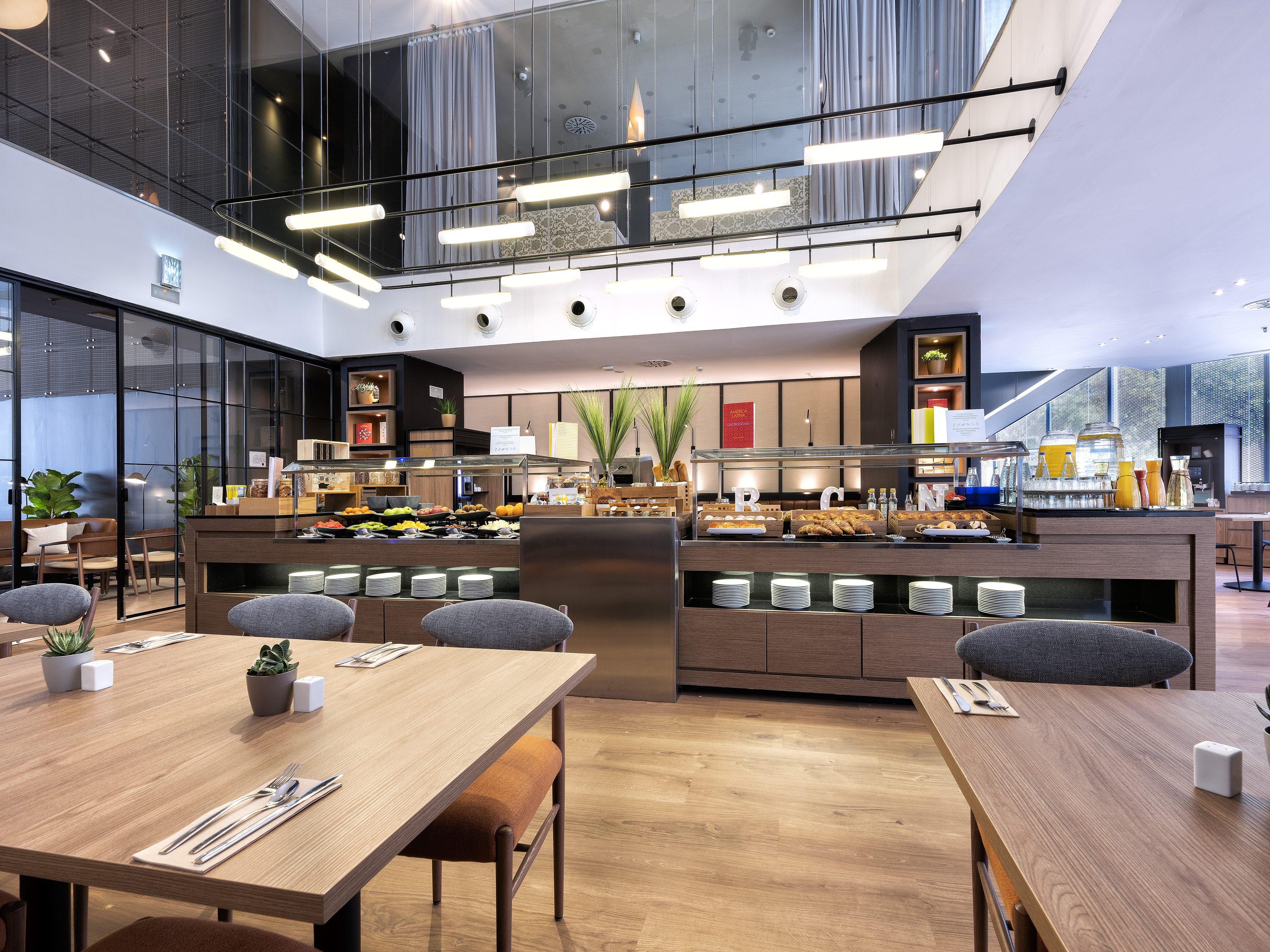 Modern hotel breakfast buffet with varied food, juices, and dining tables. - مطعم متوسطي, المطبخ المتوسطي - فندق برشلونة كوندال مار(Condal Mar) المنتسب لـ Melia, برشلونة