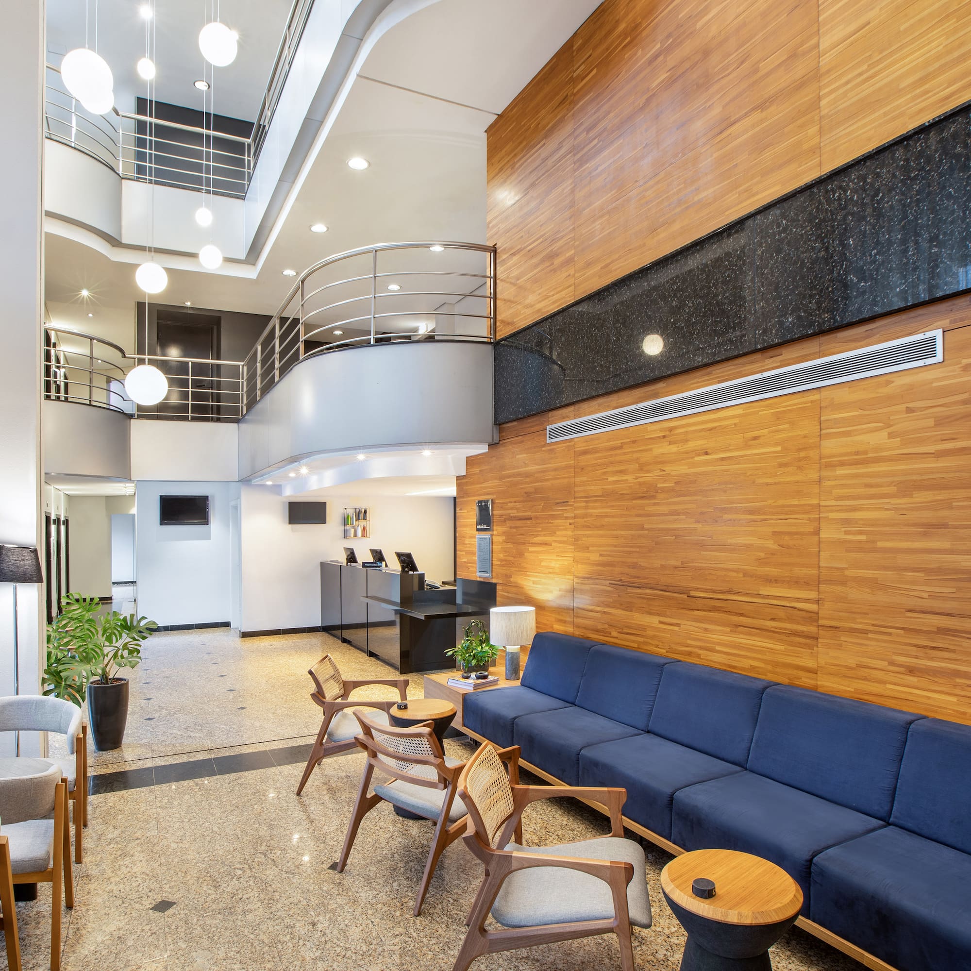 Sleek hotel lobby with blue lounge seating, wood paneling, and reception. - São Paulo Tatuapé Affiliated by Meliá, São Paulo