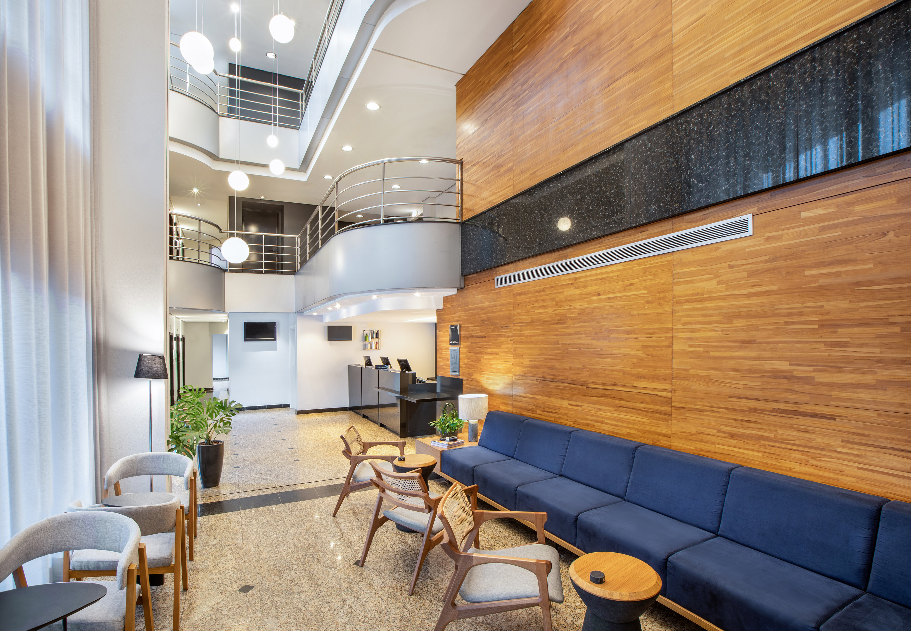 Modern hotel lobby with blue sofa, wooden walls, and multi-level atrium.