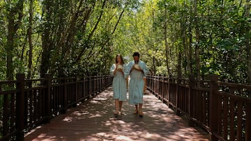 a man and woman in robes walking on a bridge with trees