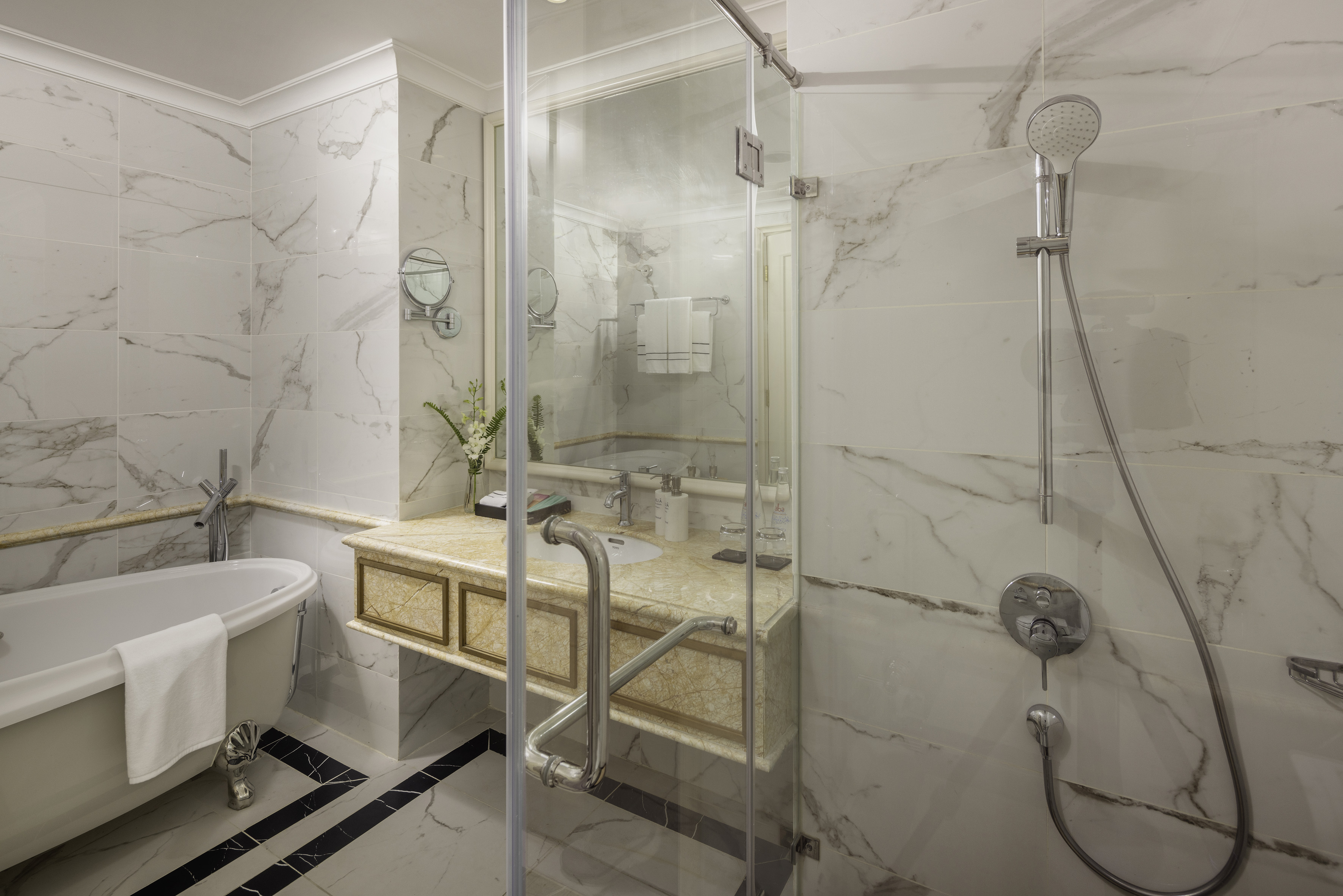 White marble luxury bathroom with clawfoot tub, glass shower, and vanity.