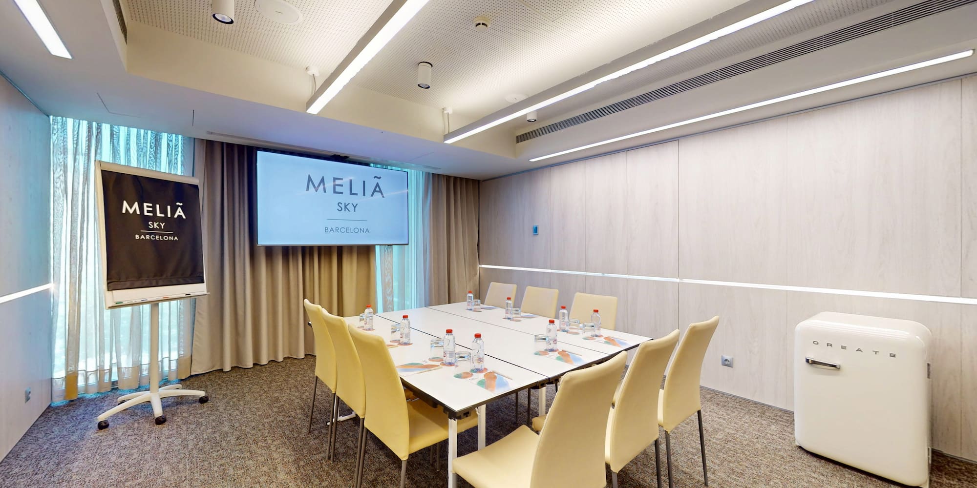 Melia Sky Barcelona modern meeting room with screen, conference table, chairs.