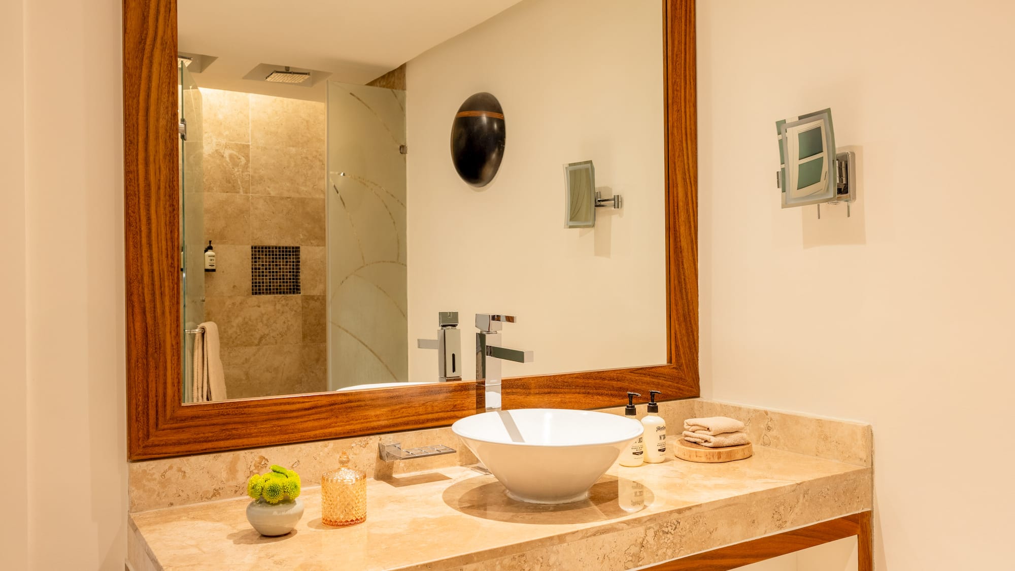 Modern bathroom vanity with marble counter, white vessel sink, and wooden mirror.