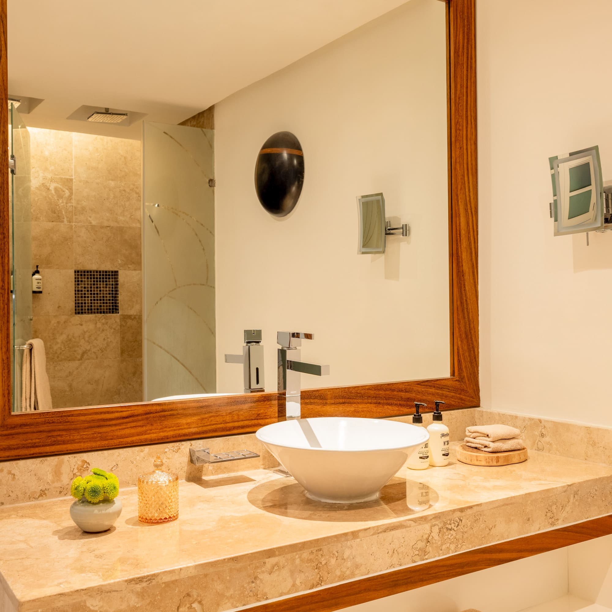 Luxury bathroom vanity with white vessel sink, marble countertop, and wood mirror.