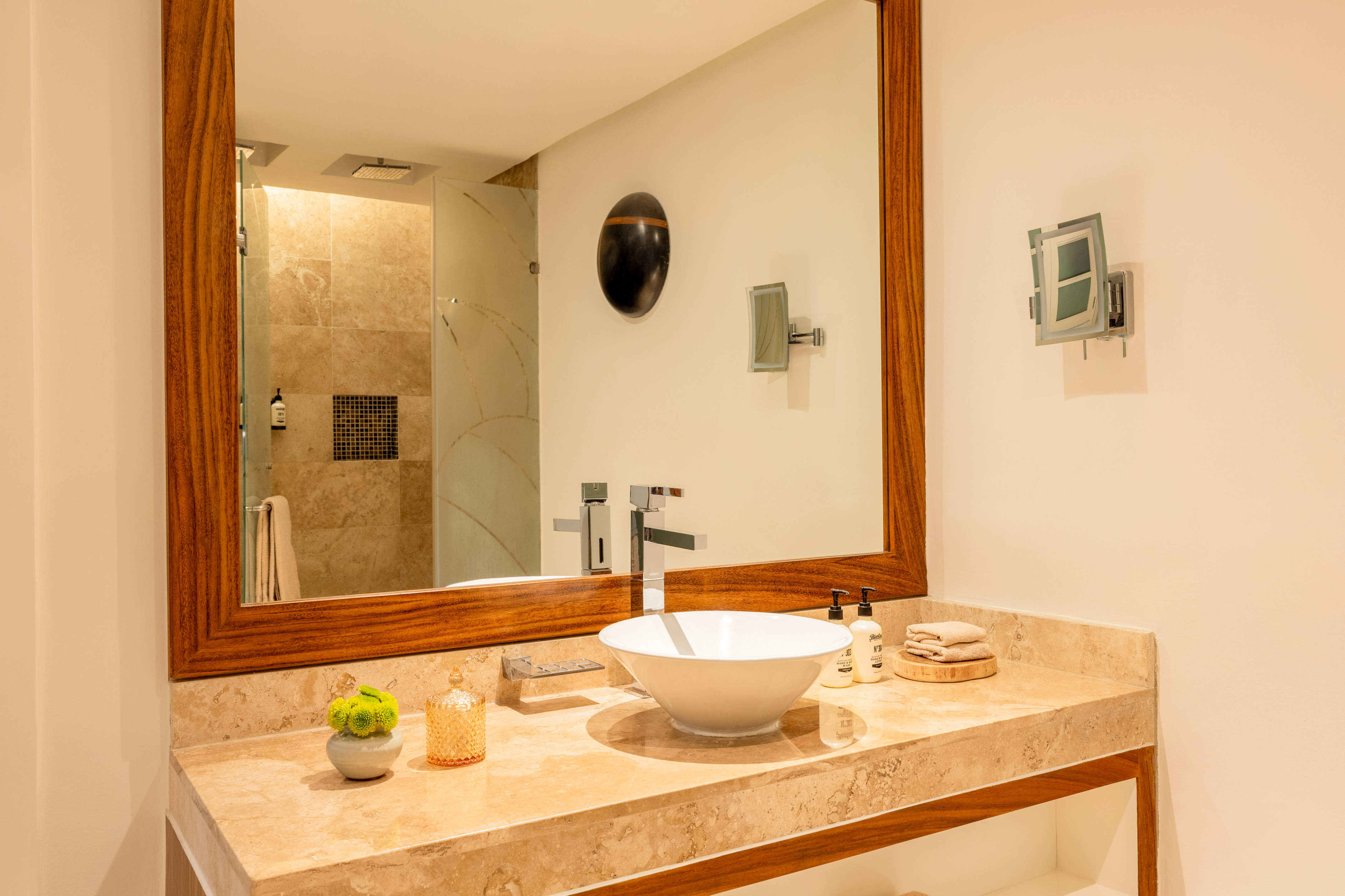 Modern bathroom vanity with marble counter, vessel sink, and wood-framed mirror.
