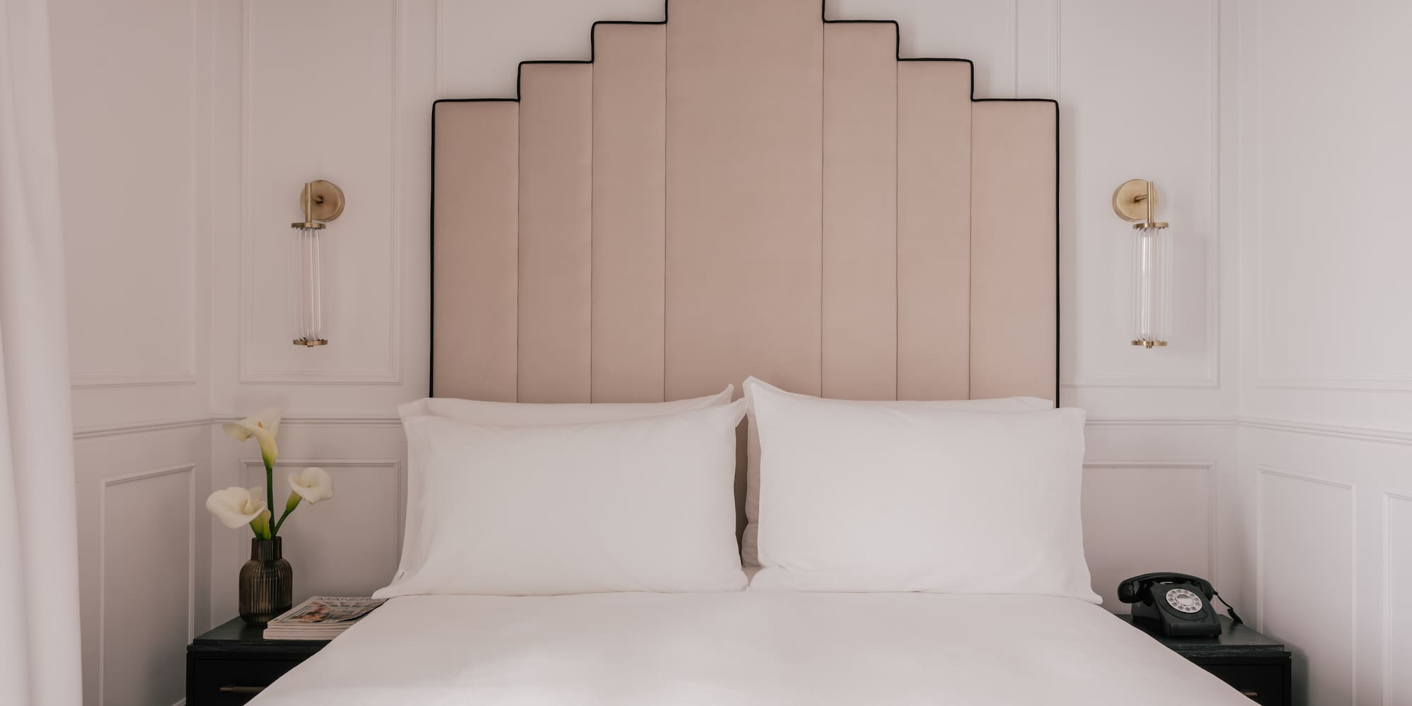 Boutique hotel bedroom with Art Deco headboard, white bed, nightstands.