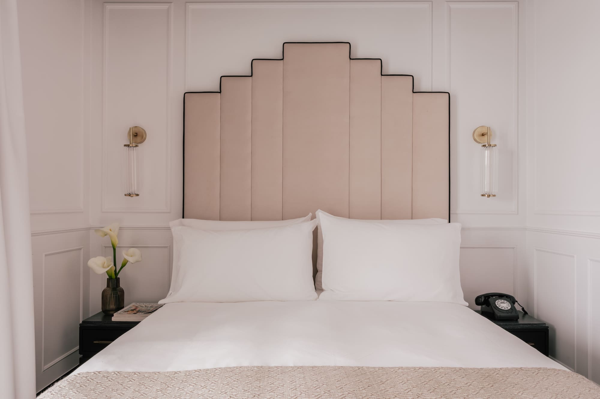 Boutique hotel bedroom with Art Deco headboard, white bed, nightstands.