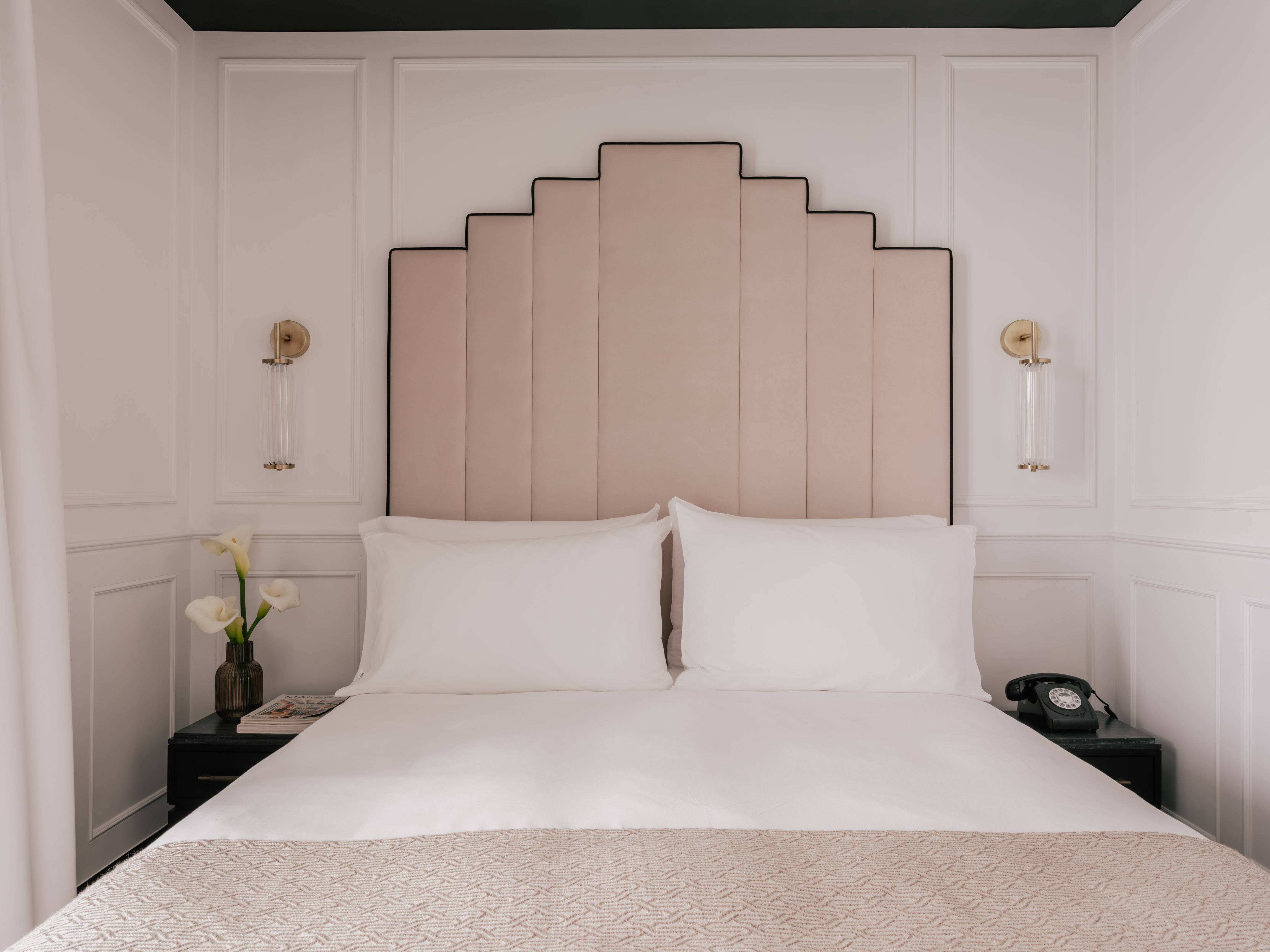 Boutique hotel bedroom with Art Deco headboard, white bed, nightstands.