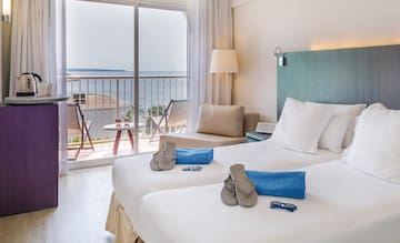 a room with two beds and a balcony overlooking the ocean