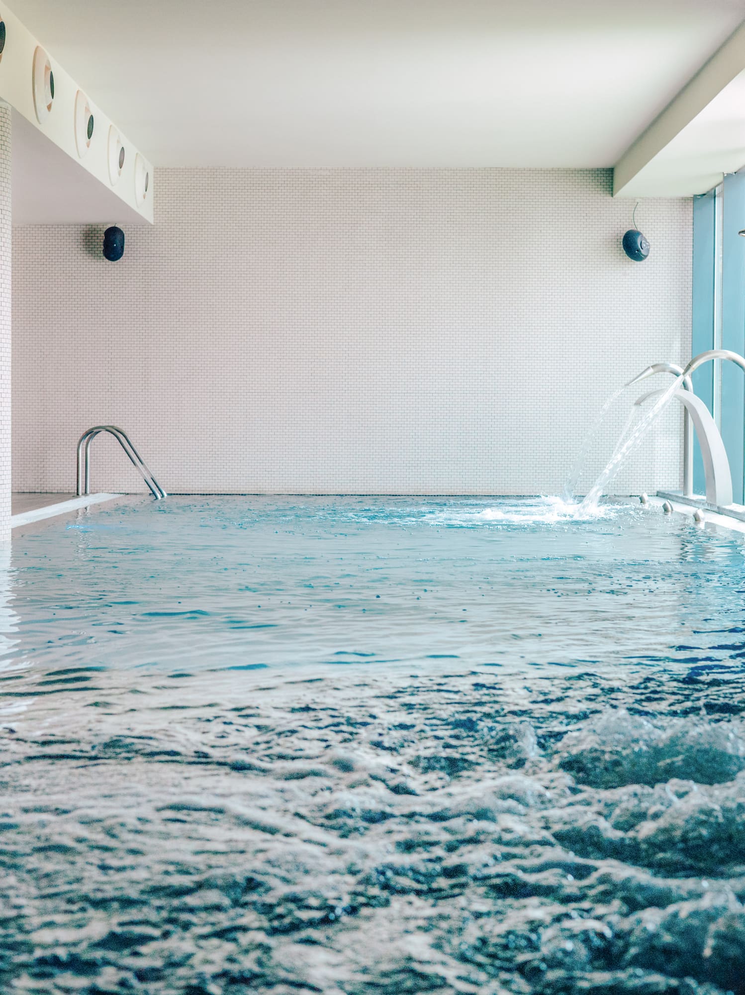 Indoor pool with bubbling water, decorative fountains, and lounge chairs.