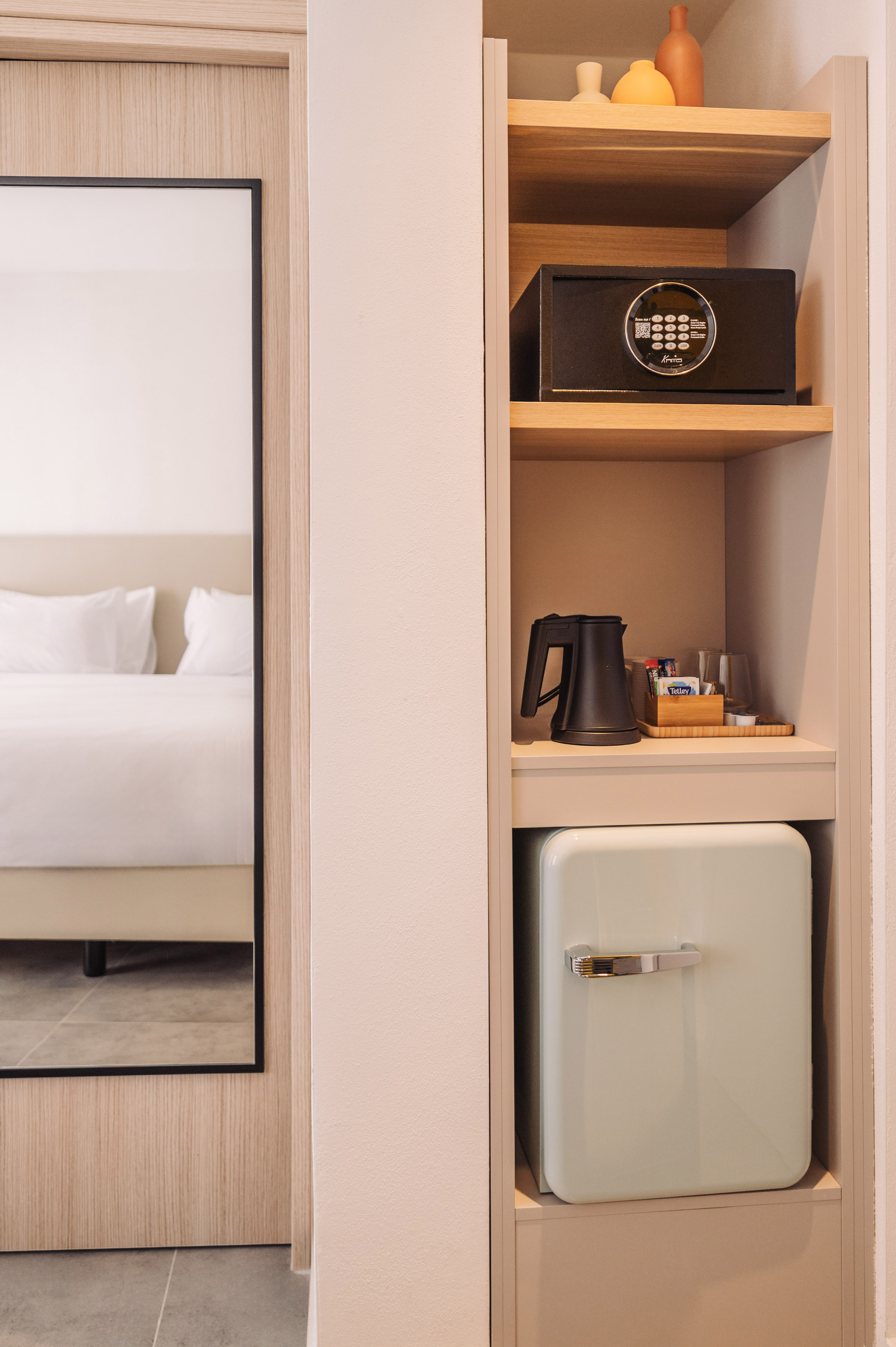 Hotel room with built-in safe, electric kettle, and light green mini-fridge.