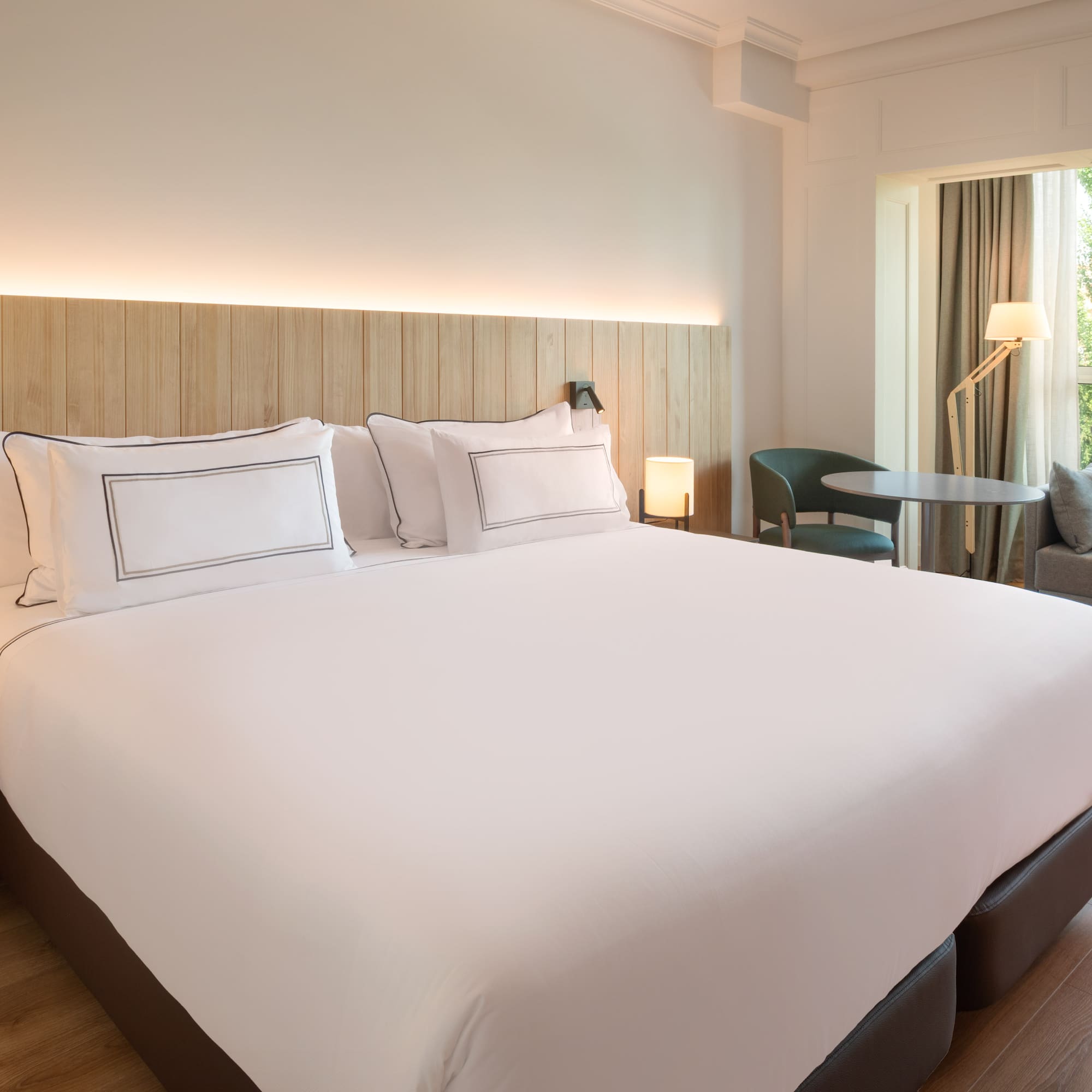 a bed with white sheets and a table and chairs