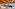 Modern hotel restaurant buffet with food, dining tables, and wood ceiling.