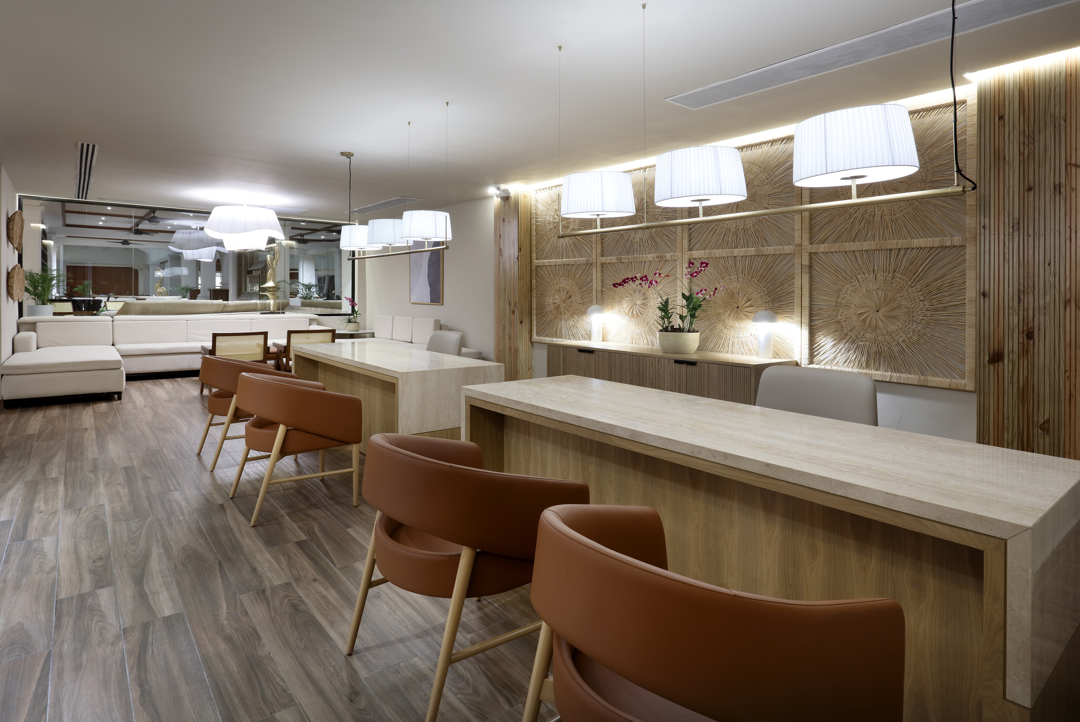 Modern hotel reception with counters, brown leather chairs, and wood paneling.
