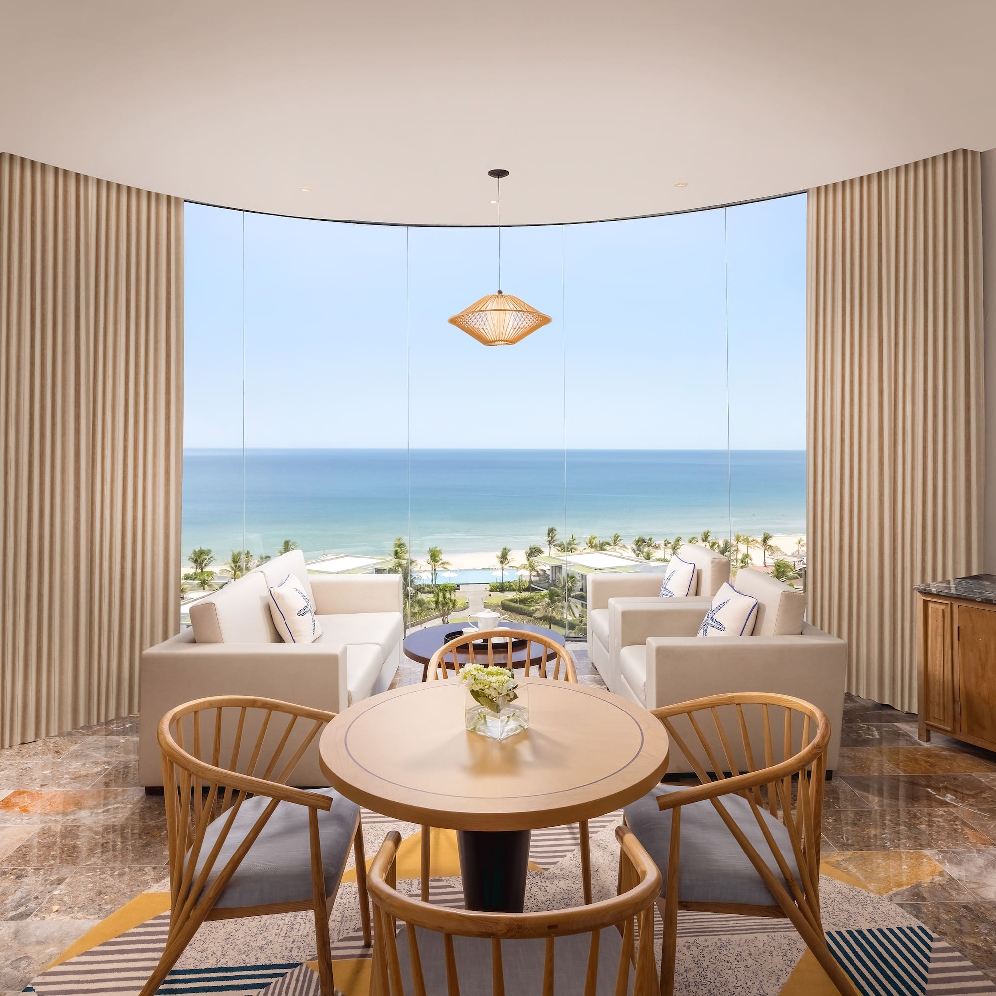 a room with a table and chairs and a view of the ocean