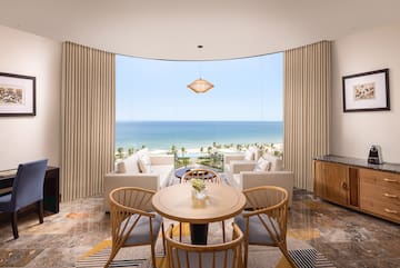 a room with a table and chairs and a view of the ocean