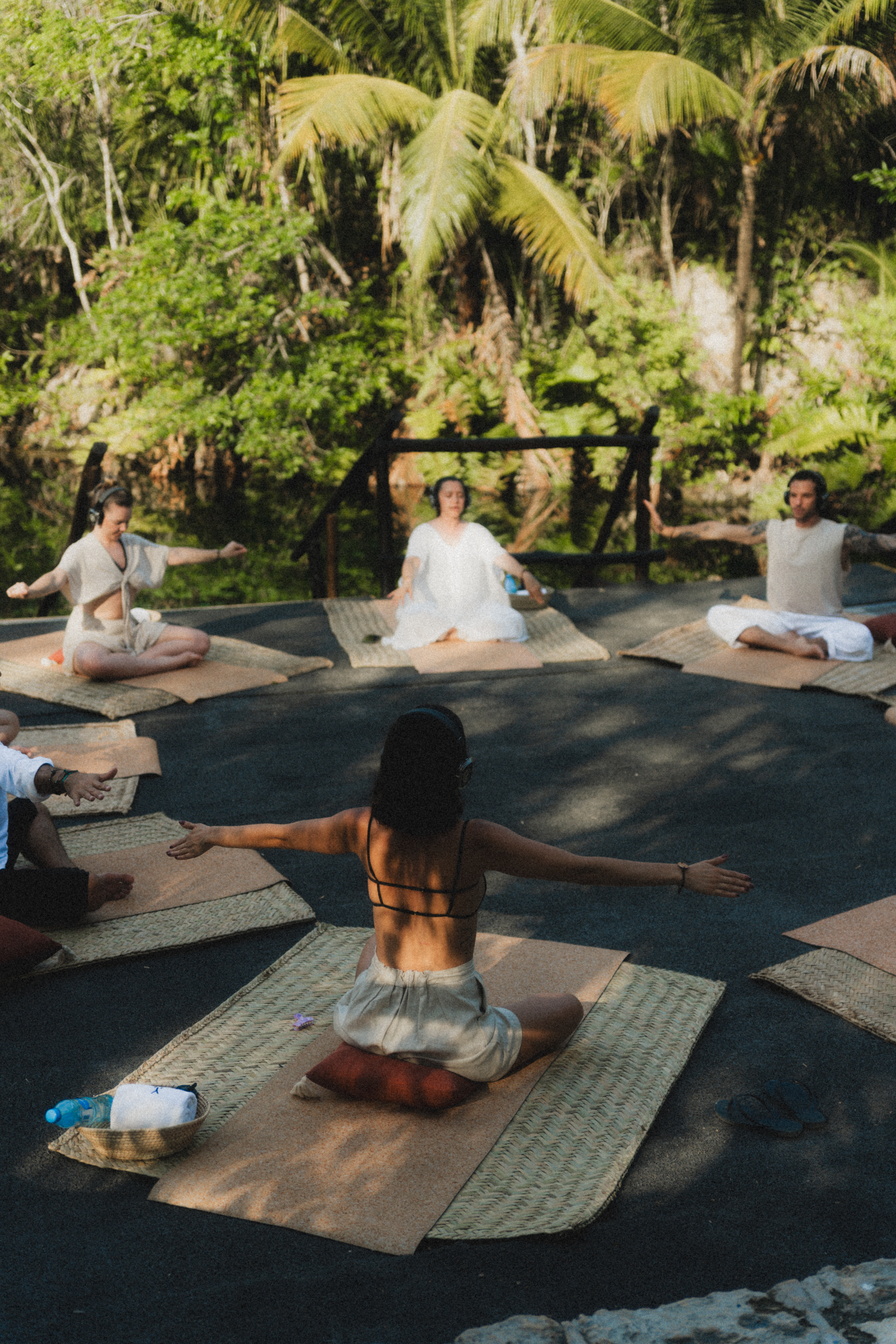 a group of people sitting on mats in a circle with trees in the background