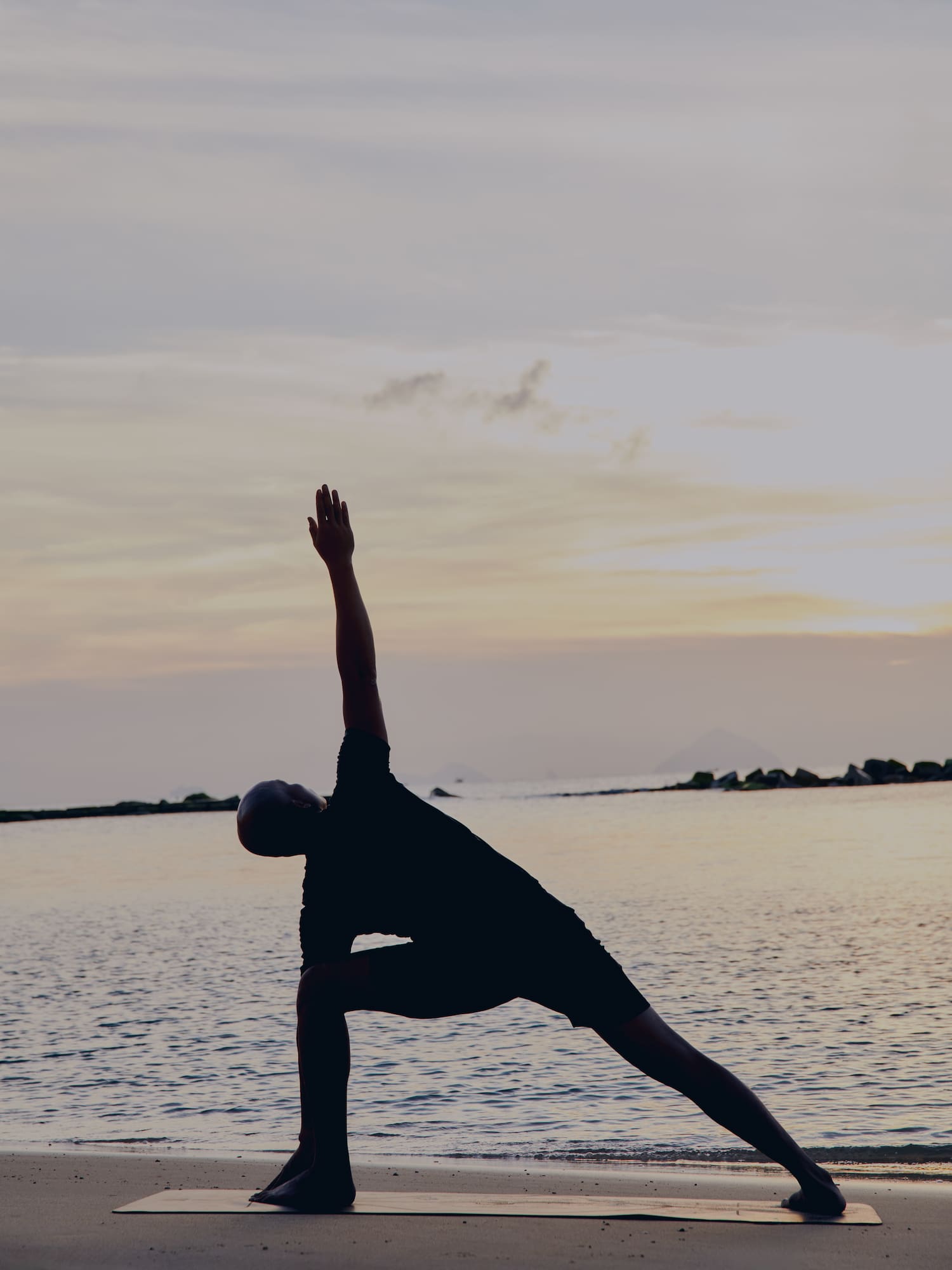 a man doing yoga on a beach